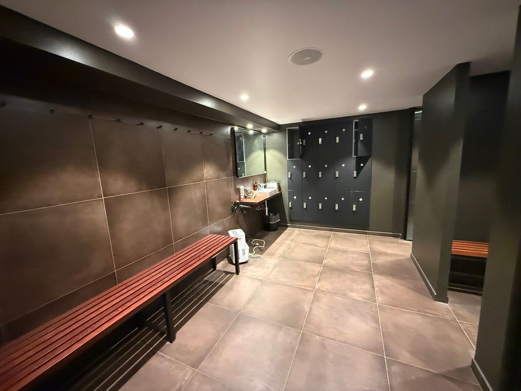 Et moderne toiletrum med brune bænke og loftsbøjler og gulv med store kvadratiske plader samt søjler med skabe til opbevaring