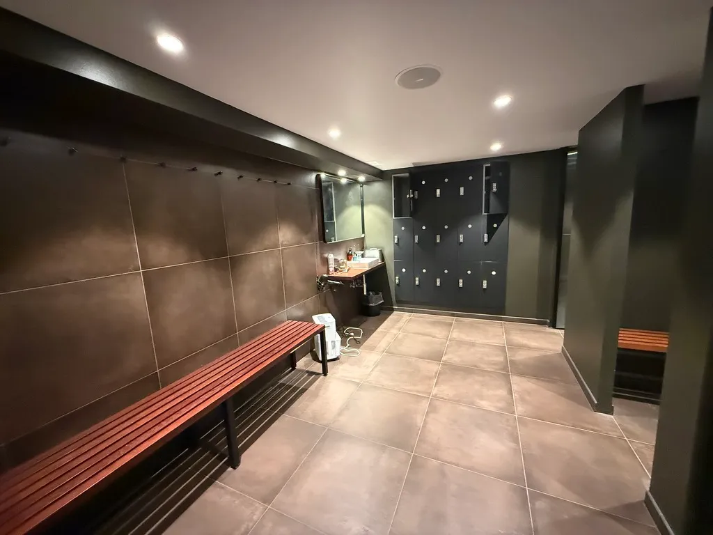 Et moderne toiletrum med brune bænke og loftsbøjler og gulv med store kvadratiske plader samt søjler med skabe til opbevaring