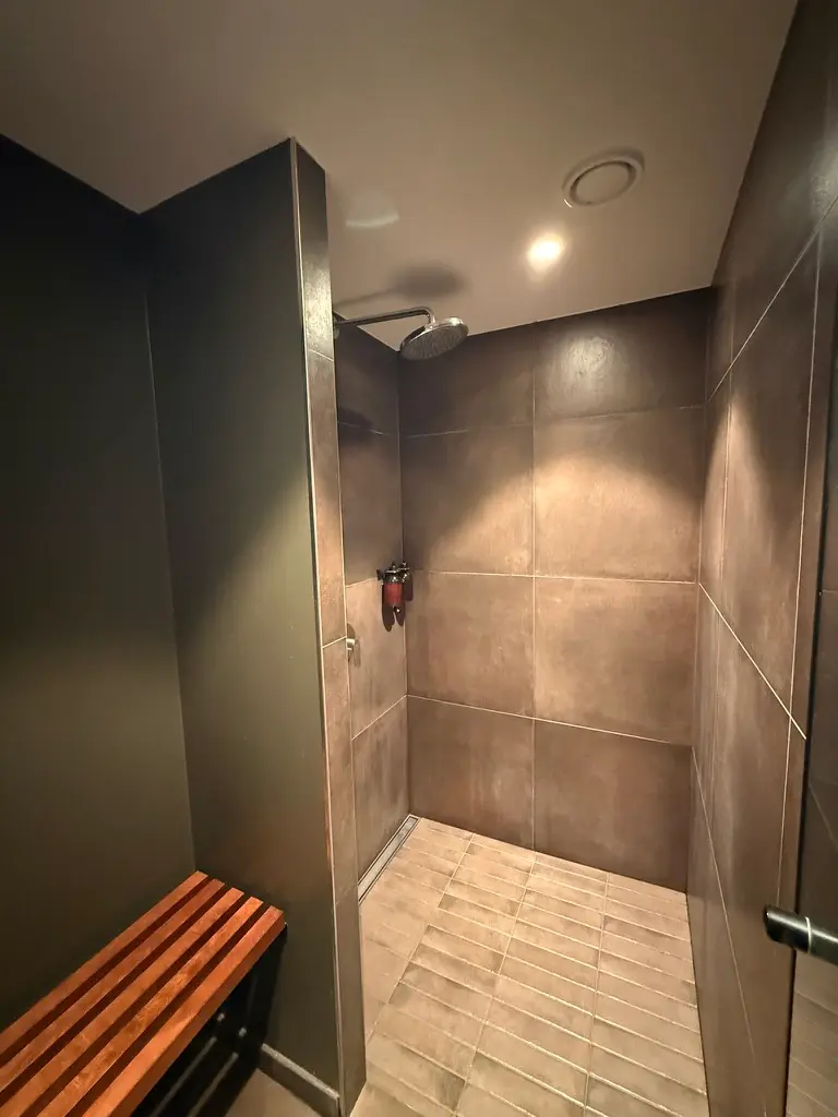 Det moderne fitness- og træningslokale på Jernbanepladsen 27 har et elegant brusebad og en træbænk til afslapning, alt i nærheden af Lyngby Station