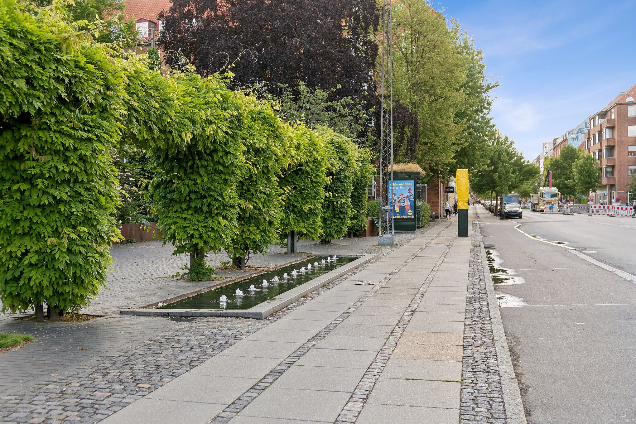 Allerede på Finsensvej i Frederiksberg ligger et butikslejemål med vandspring, grønne træer og smukke huse langs vejen