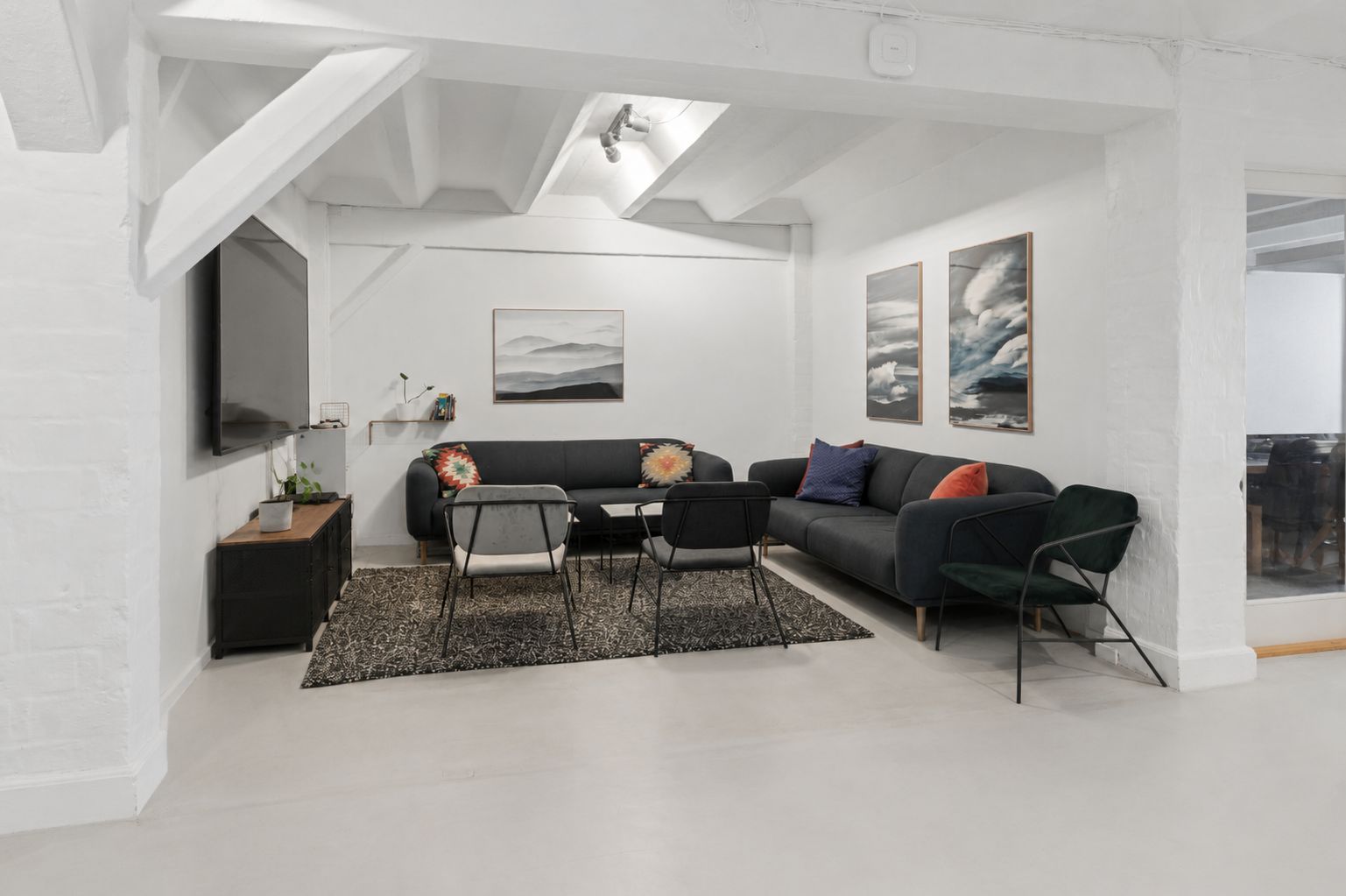 Et kontorlejemål på Njalsgade med højloft, sofaer og stole, tv og møbler samt lyse loftslamper og store vinduer