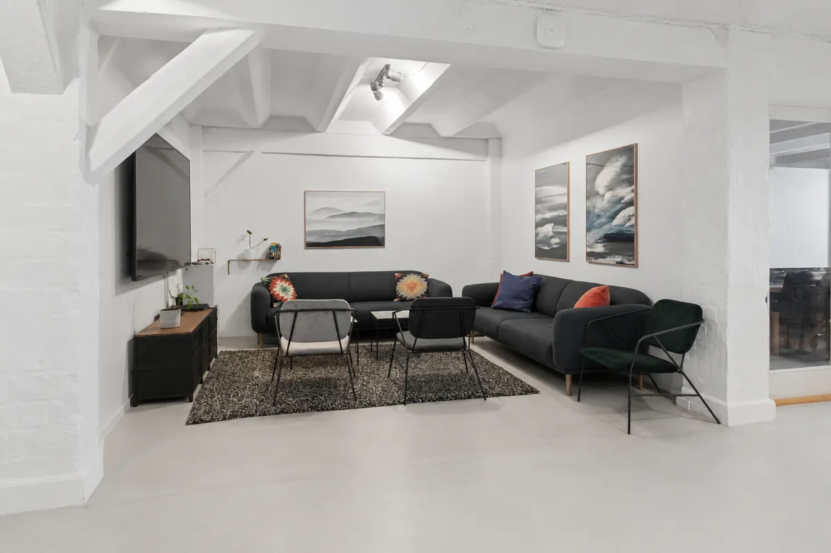 Et kontorlejemål på Njalsgade med højloft, sofaer og stole, tv og møbler samt lyse loftslamper og store vinduer