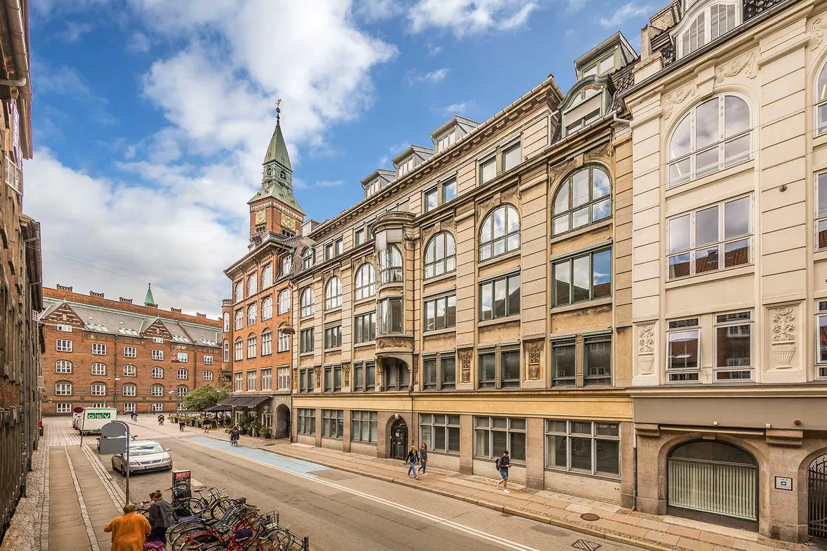 Lyst og charmerende kontor i klassisk københavnerejendom med flot udsigt over byens tage og tårne. Mennesker går på gågaden og parkerer biler.