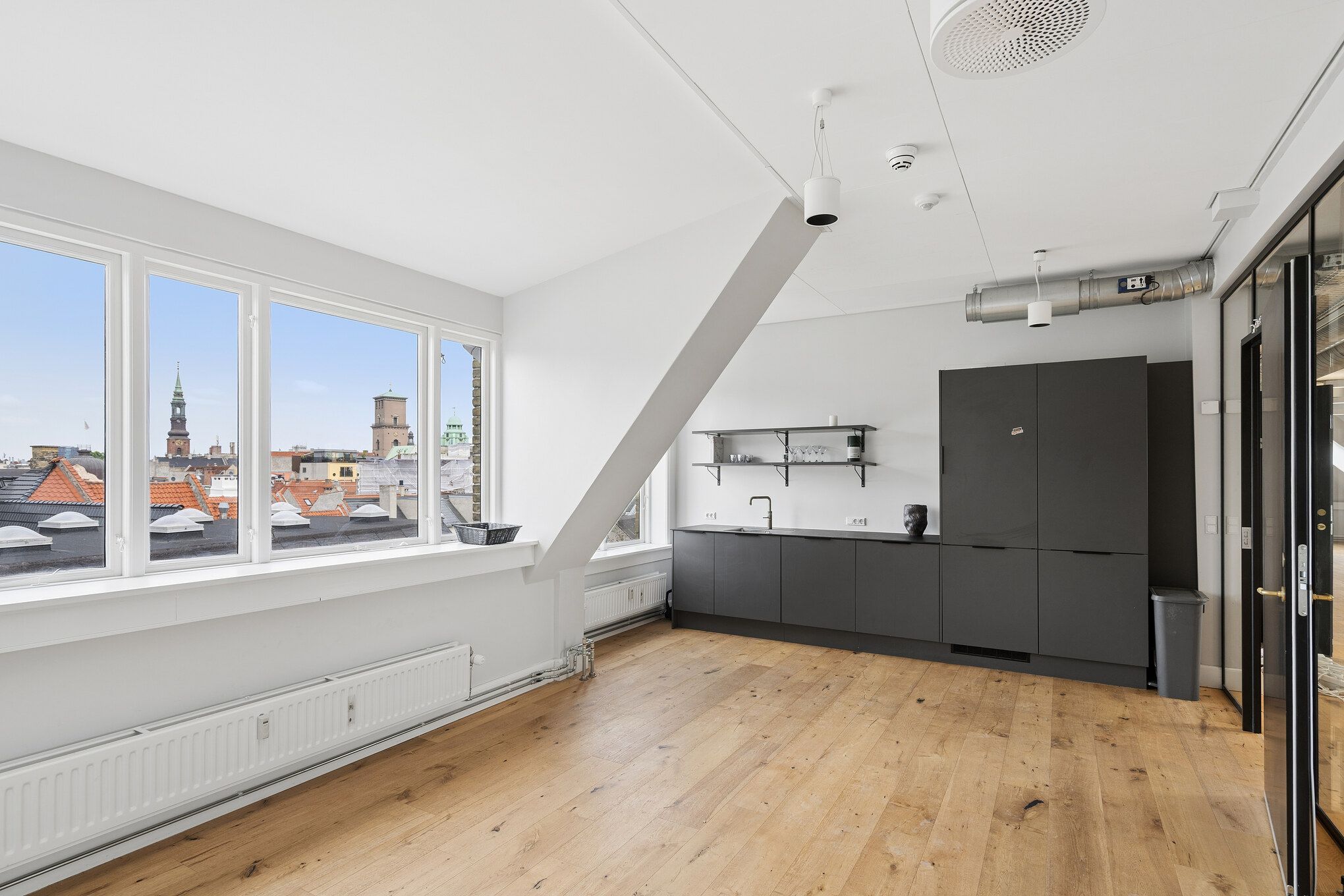 Lyst og charmerende kontor med udsigt over Københavns tage og tårne. Det er en klassisk ejendom med højloft og trægulv