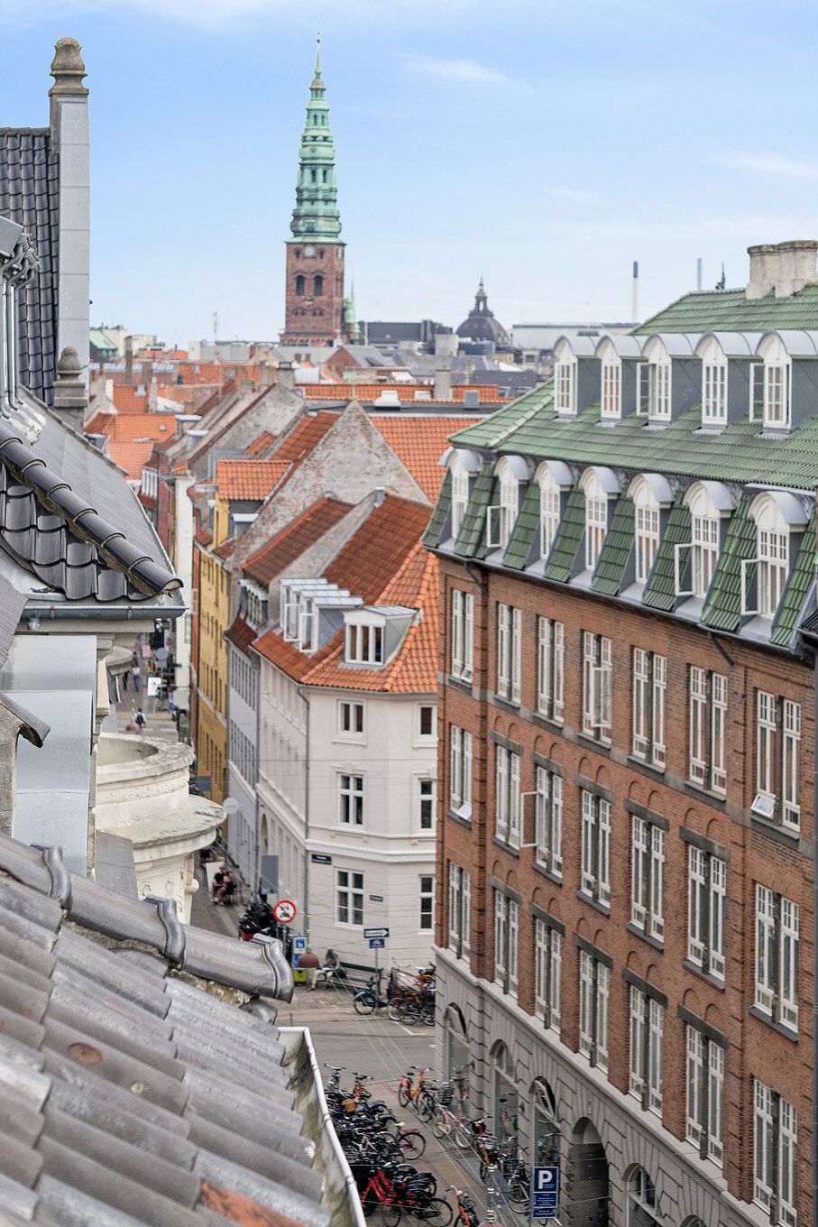Lyst og charmerende kontor med udsigt over byens røde tage og tårne. Parkerede cykler, bygninger med forskellige facader og smukke røde tagdækninger.