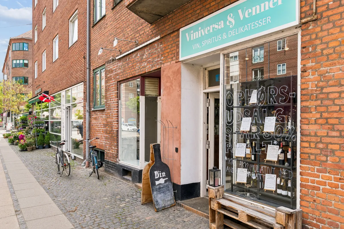 En butik med vinflasker og ølflasker i vinduet og to cykler parkeret foran døren