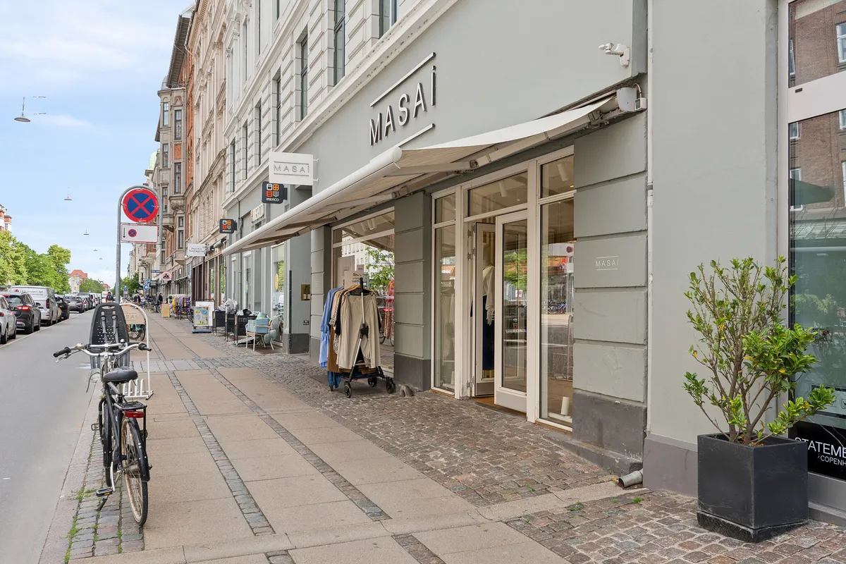 Butik i hjørne med navnet Masa, med klædespind og tøj i udstillingen og cykel og plante foran.