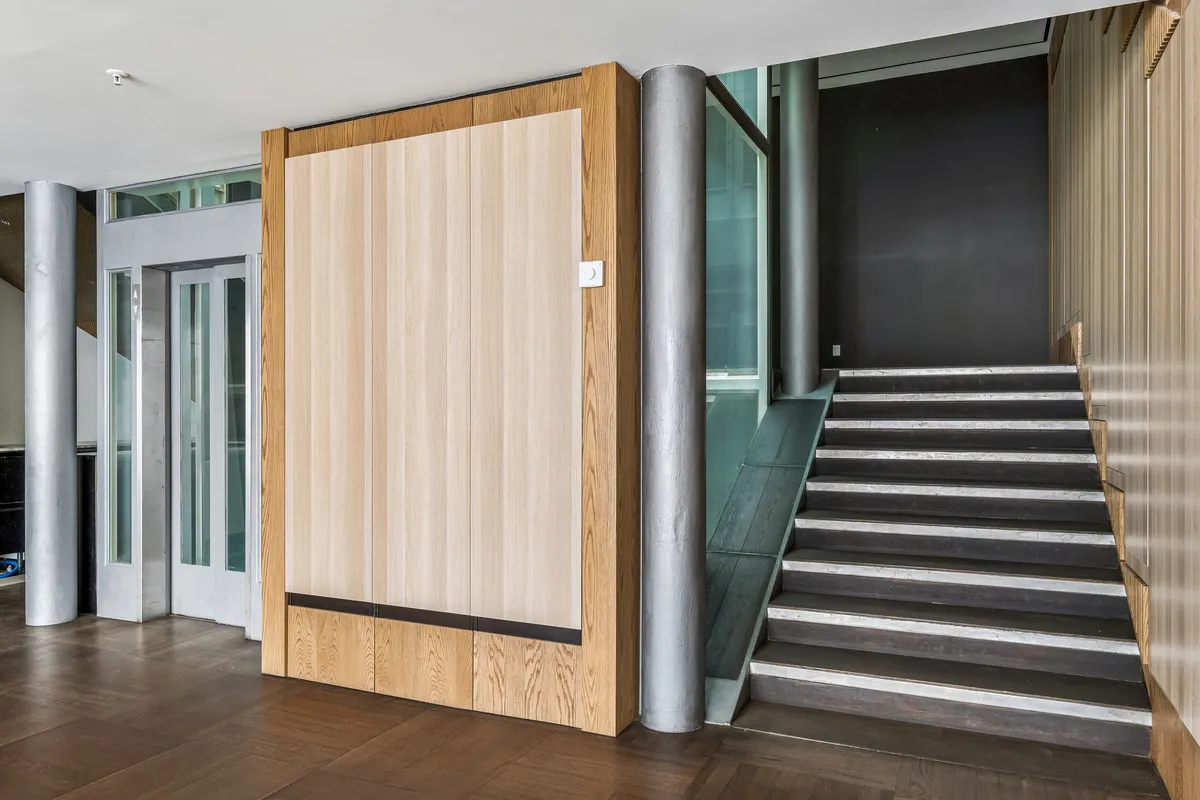 Et moderne kontor med højloft, træpaneler og højkvalitets gulv. Stigende trapper og elevator. Moderne døre og glasvinduer. Minimalistisk design med lyse nuancer