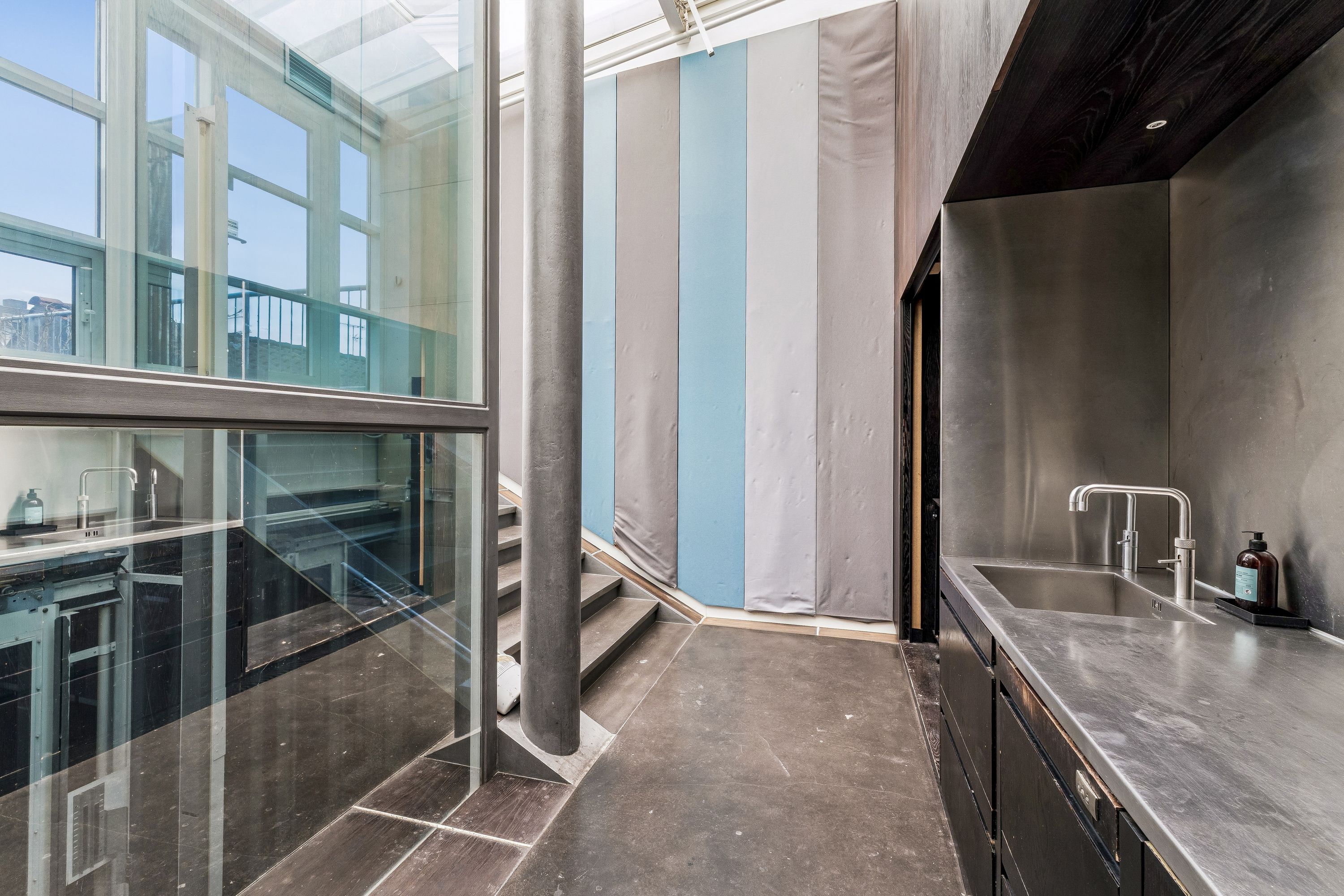 Lejlighed til leje med glasveranda, hvid-blå kurtinene og mørke træskabe. Moderne design med rustfrit stål overflade og to vandhaner.
