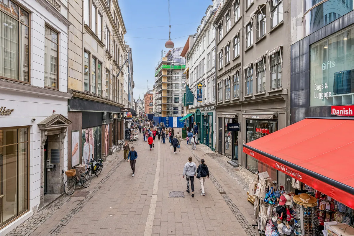 Gå forbi butikkerne og stig op på Østergade. Gå forbi de forskellige butikker og mærker, herunder Max Mara og Diesel. Gå forbi de mennesker, der køber souvenire i butikkerne.