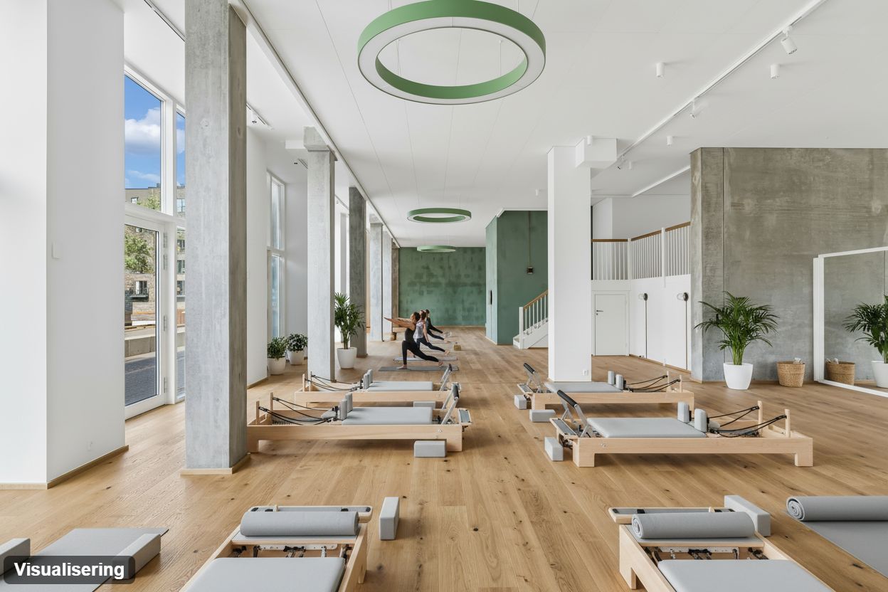 Trægulv og moderne møbler i et pilates-studie med tre øvelsestalter, plantager og runde loftslampe