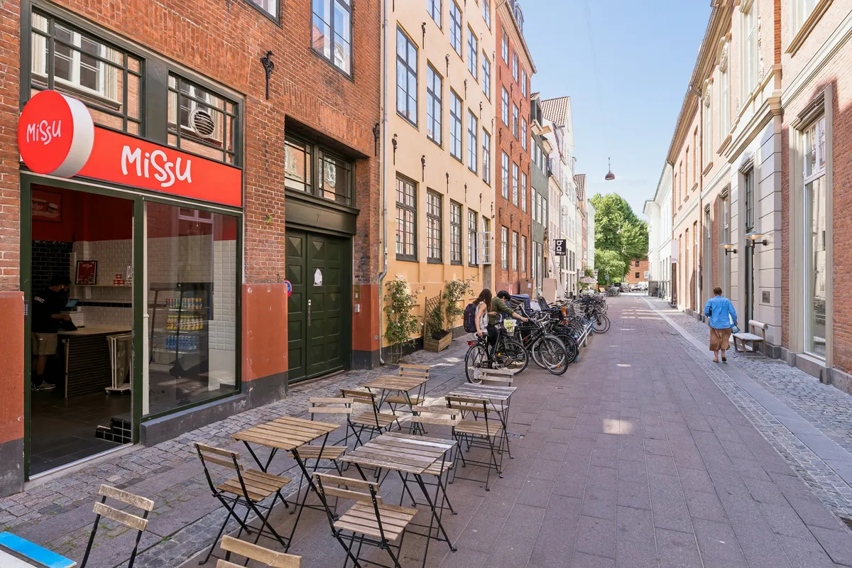 Valg af smukke terrasseborde med stole udenfor restauranten Missu i København. Baggrund med rød facade og grønt vindue