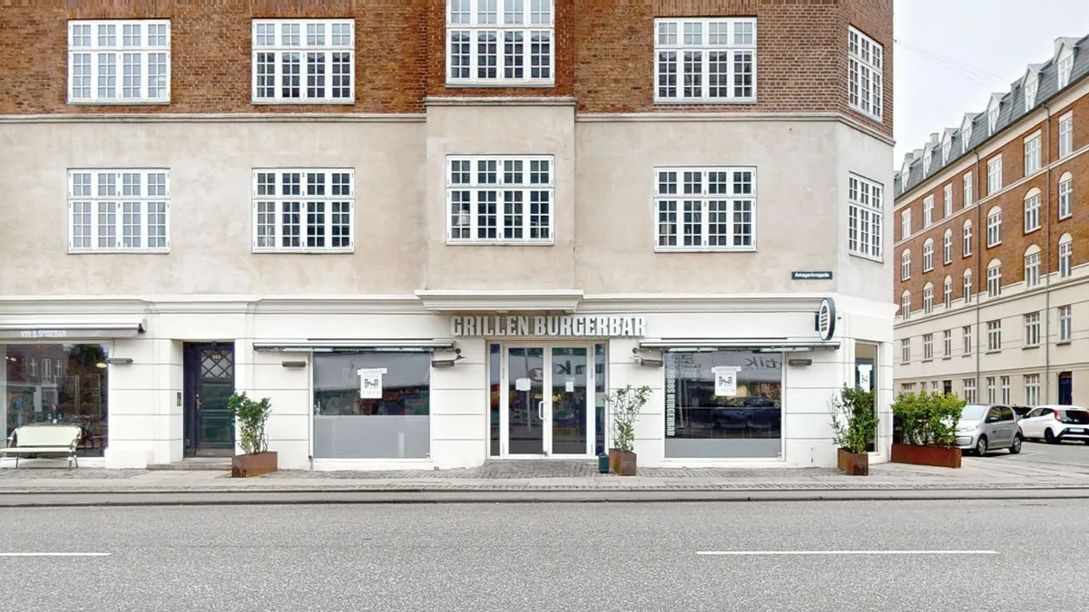et restaurantlejemål med store vinduer og lyse facader på Amagerbrogade 145. Der er lyse køkkenvinduer og moderne indretning. Restauranten er velbesøgt og ligger på en travl gade.