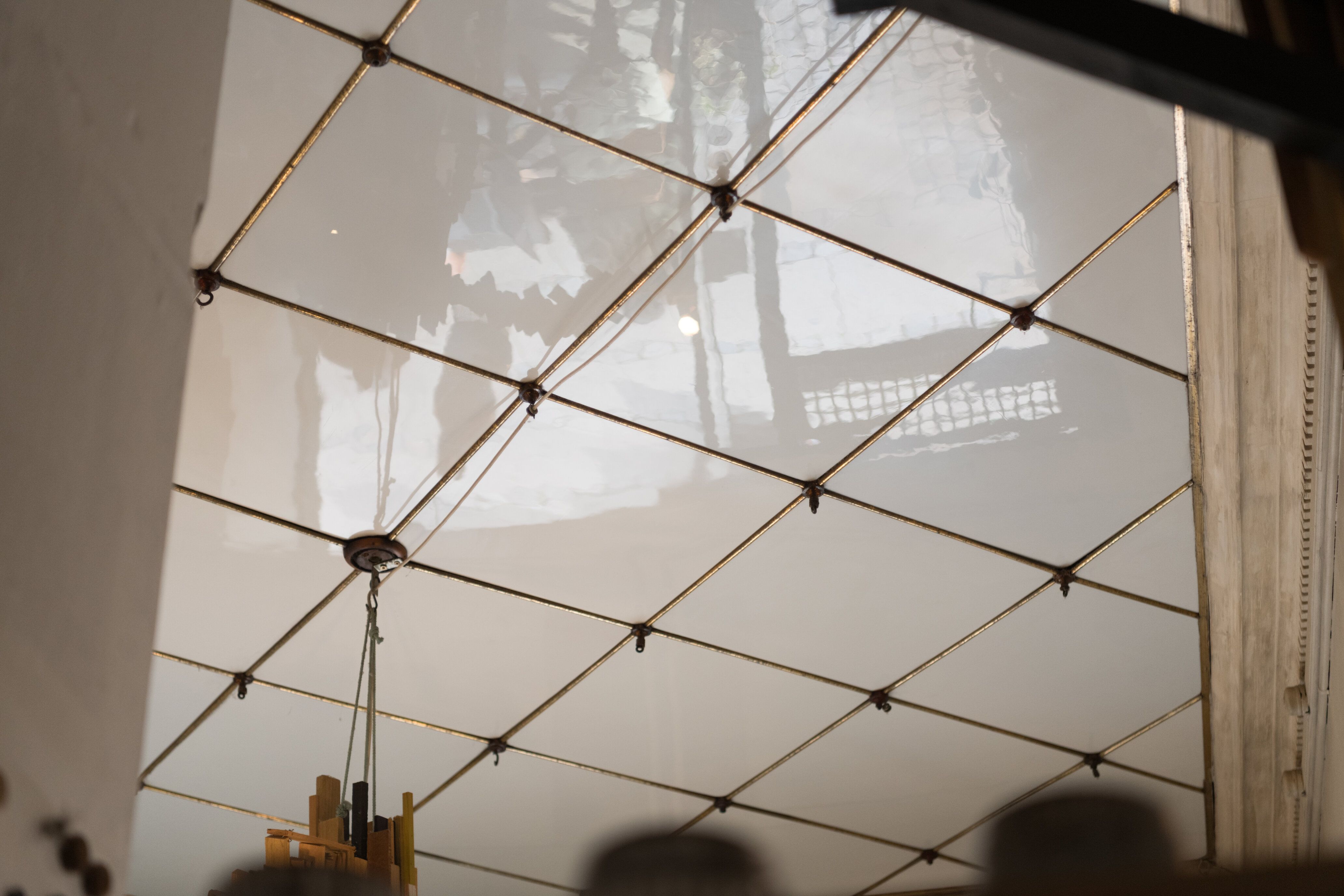 Glas loft med guldbeger og hængende lysekrone. Detaljer med refleksioner og mønstre.