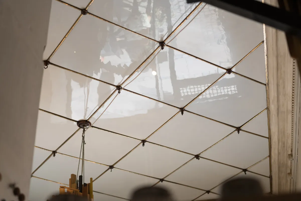 Glas loft med guldbeger og hængende lysekrone. Detaljer med refleksioner og mønstre.