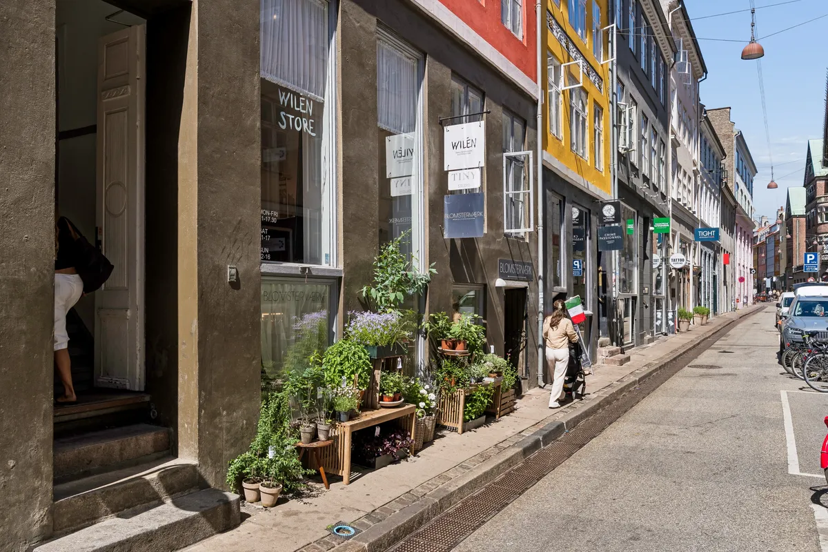 Butik med blomster på terrassen og mand og barn går forbi på gaden i København