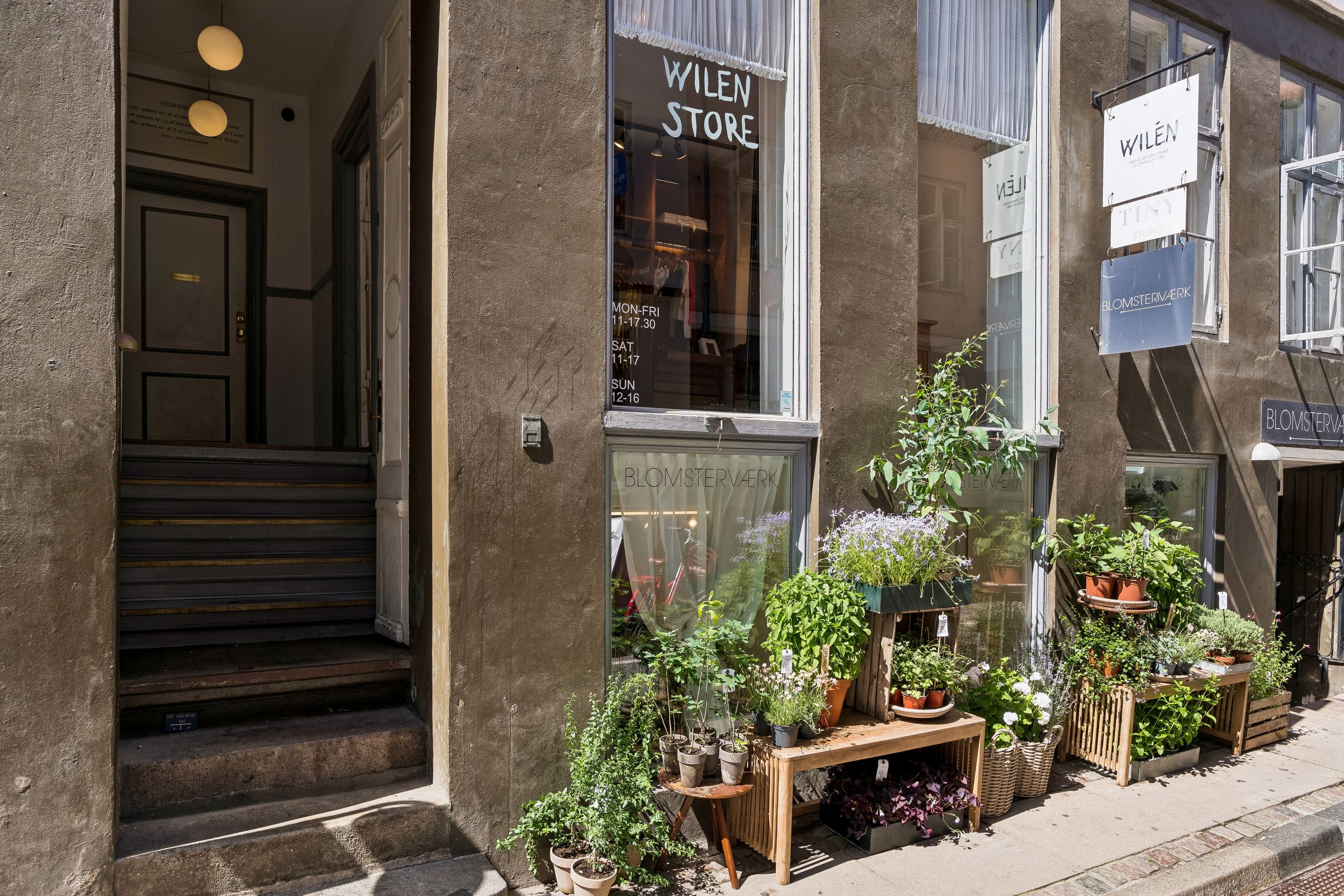 Blomsterværk og modebutik på Hyskenstræde i København K, med udskåret tekst og plantehygge på fortovet