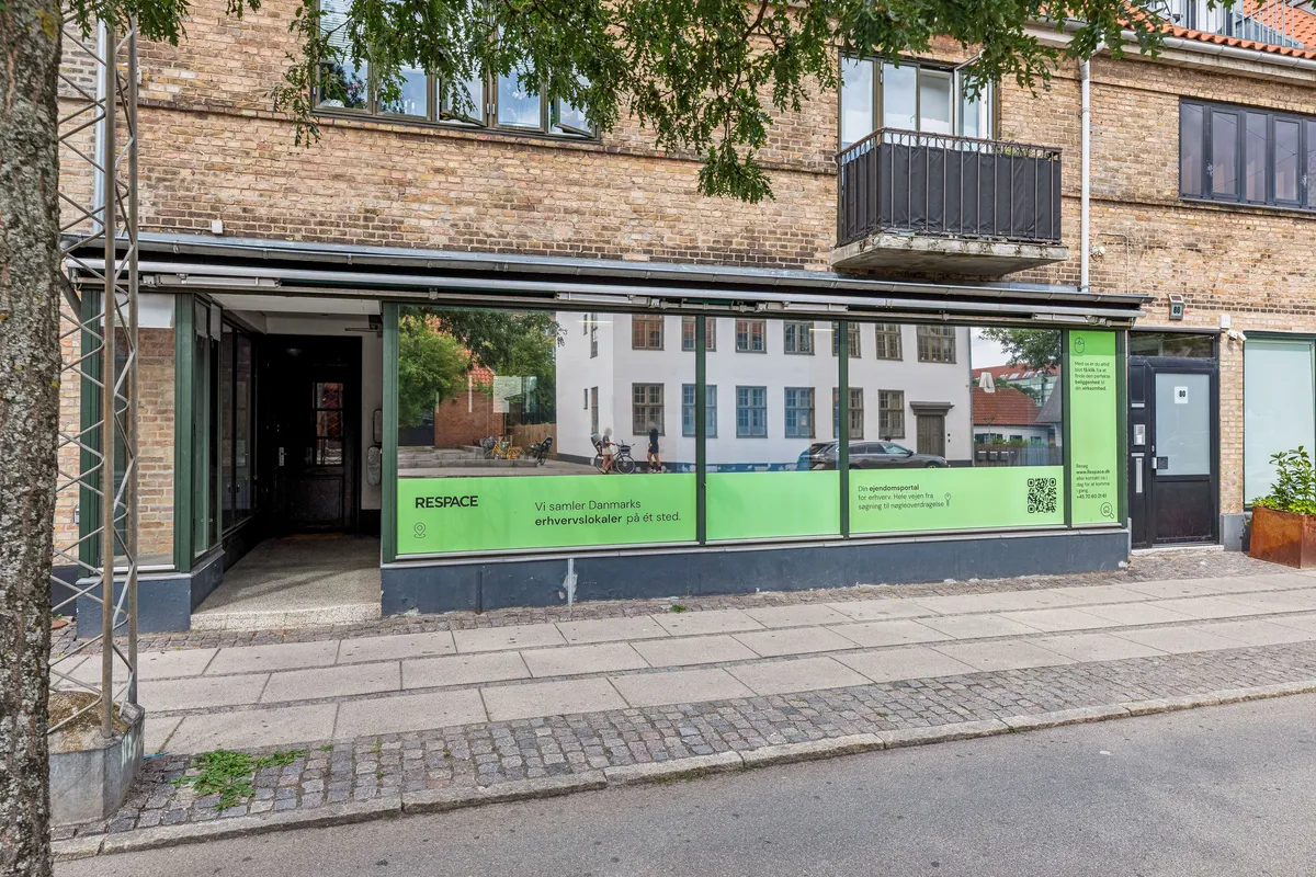 Kontor til leje på Godthåbsvej 82, Frederiksberg. Bygningen har store glasruder og står ved siden af slagterbutikker og sportsforretning. Der er en QR-kode på facaden.