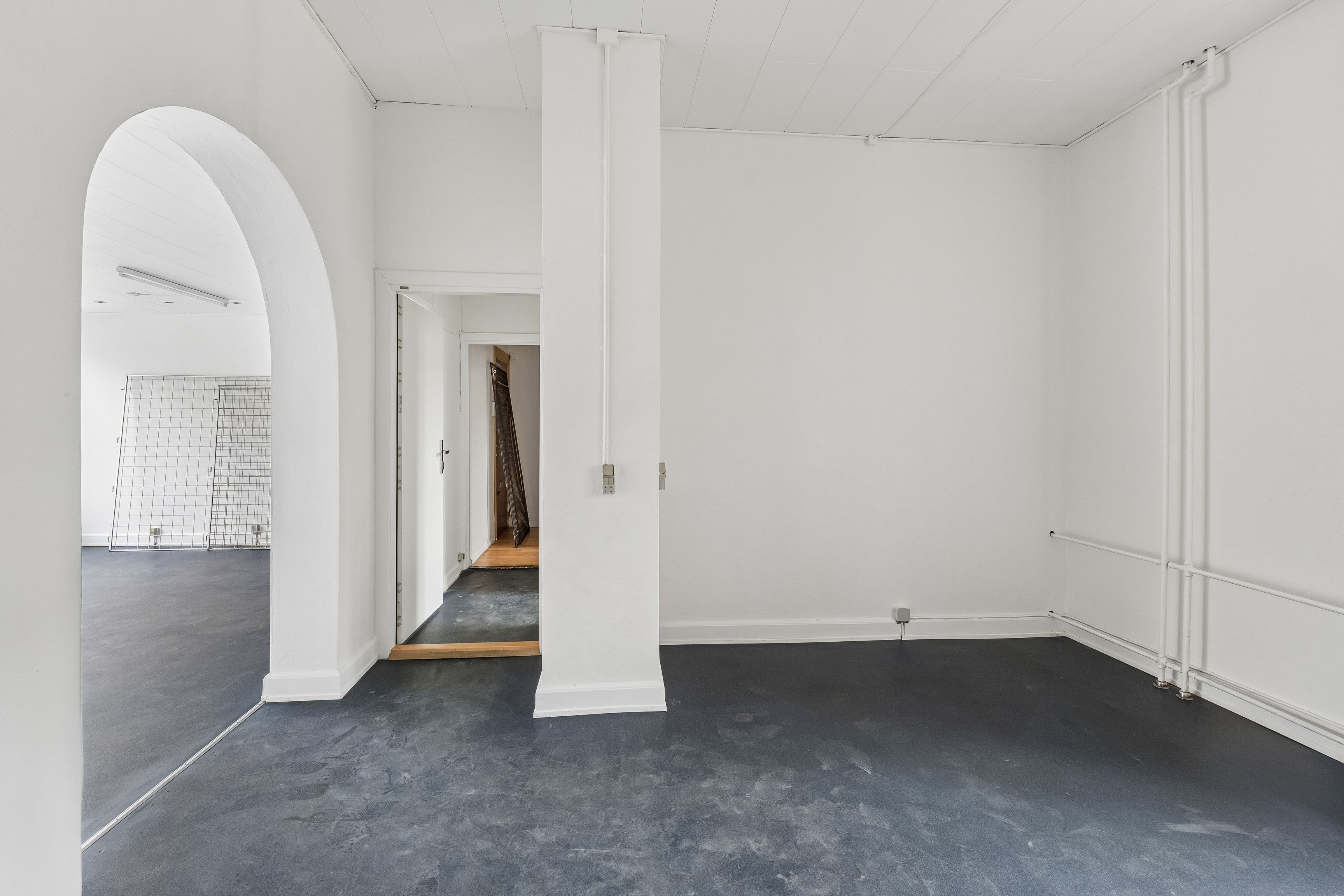 En stor, lys, tom og ren forretningslokale med hvide vægge og højt til loftet