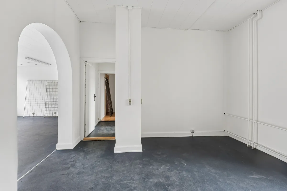 En stor, lys, tom og ren forretningslokale med hvide vægge og højt til loftet