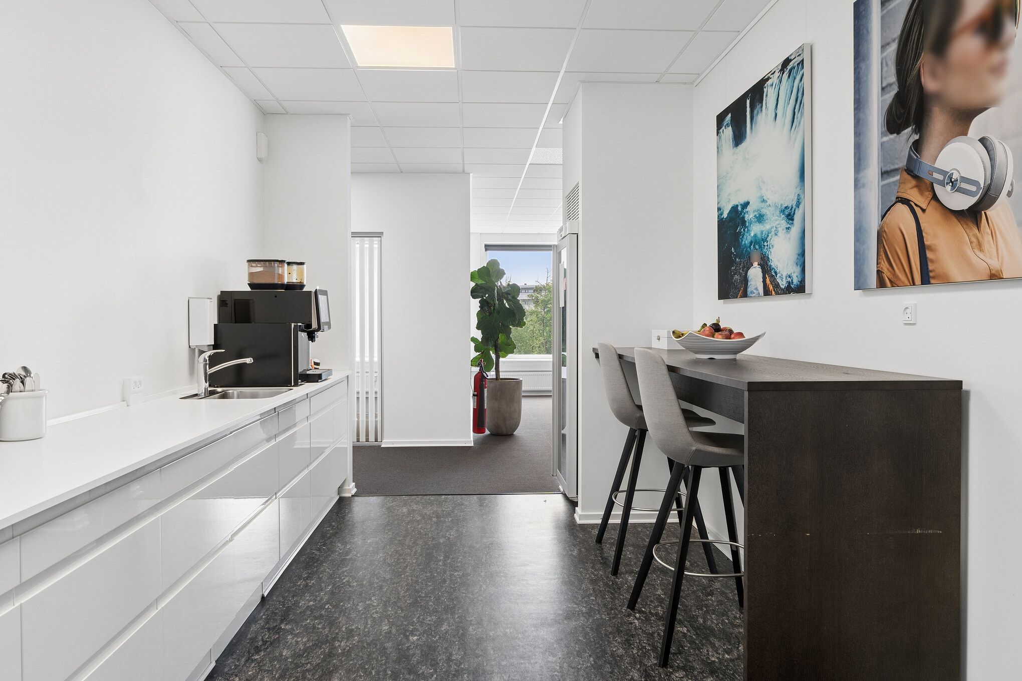 Køkken med højloft, moderne udstyr, køleskab, stol, højtalere, malerier og gulvbelægning