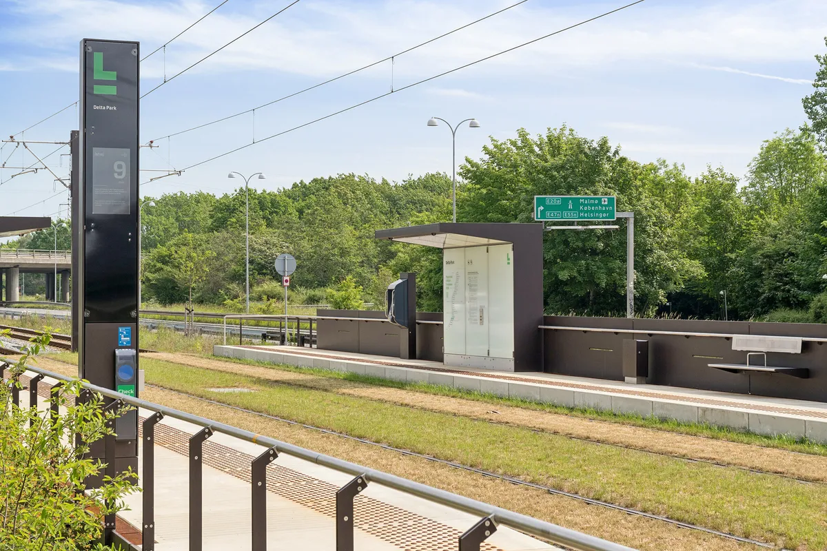 Søjle med skilt for Delta Park, der viser vejvisning til Malmö, København og Helsingør, samt et moderne kontorlokal, der har en kantine, mødecenter og bemandet reception