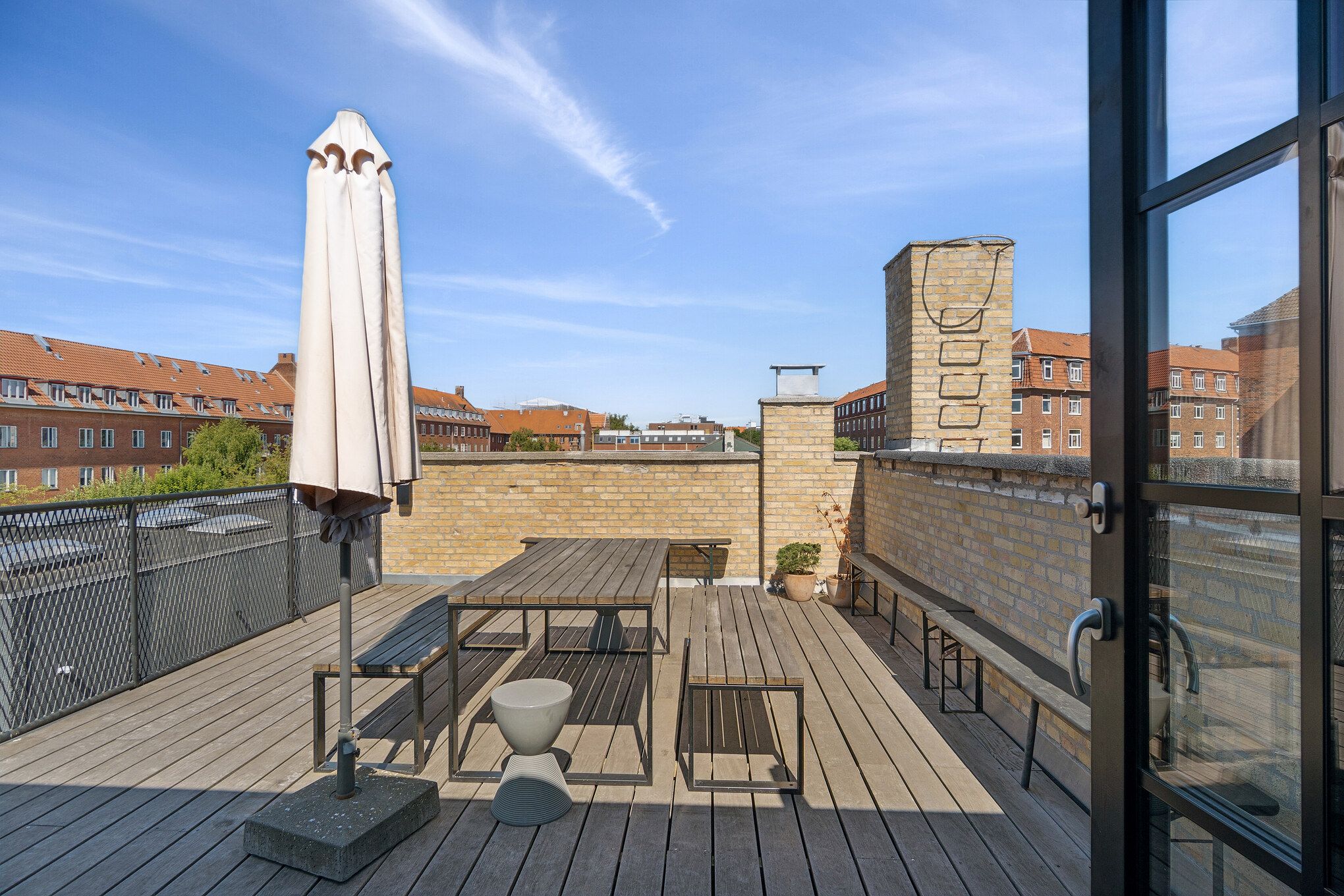 Solskin og lyse himmel på terrasse med udendørs møbler, stol, bord, parasol og små plantepoter