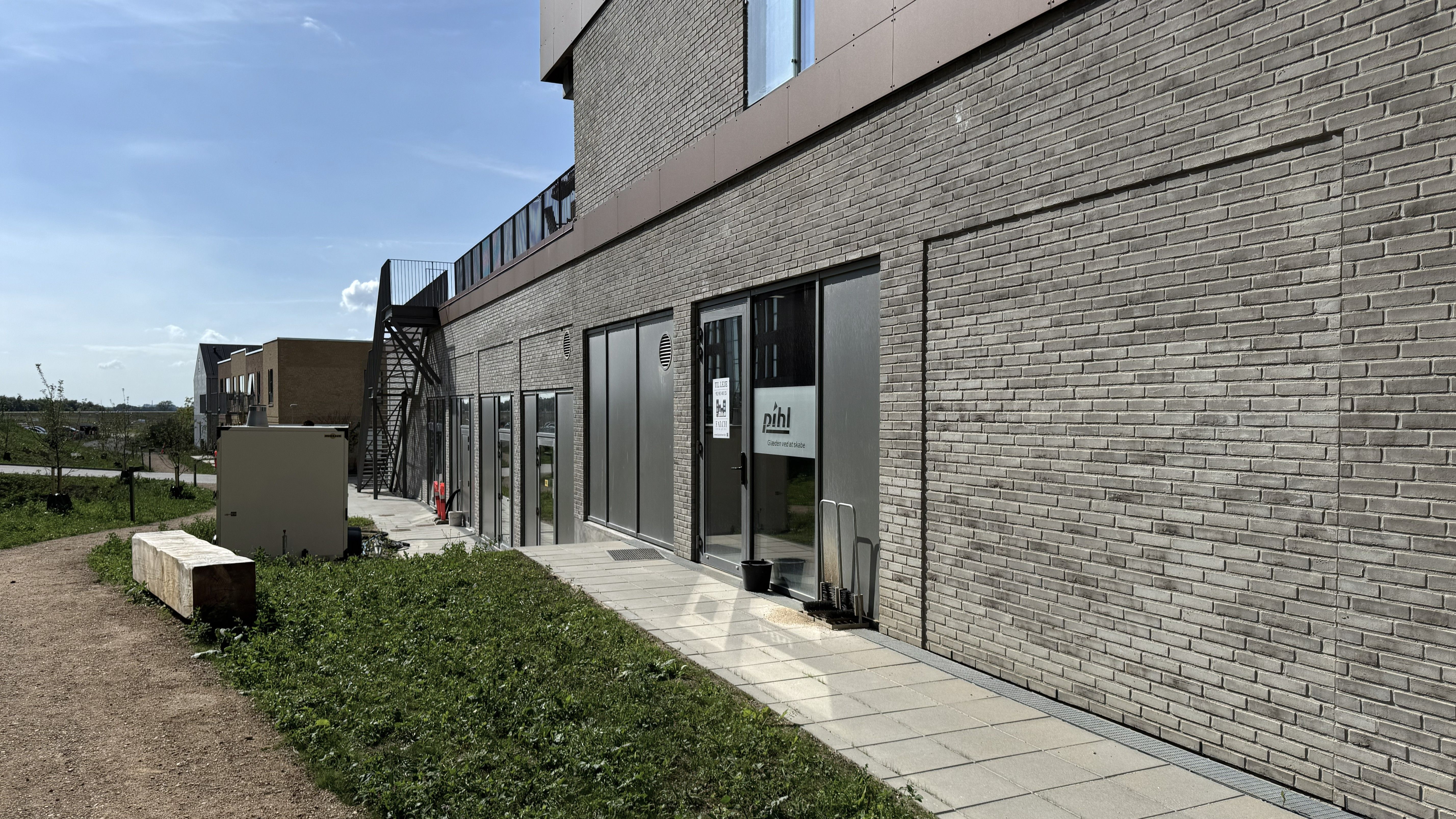 Moderne erhvervslejemål på Vinge Stationsvej 23 med terrasse, store vinduer, skilte og grønne omgivelser