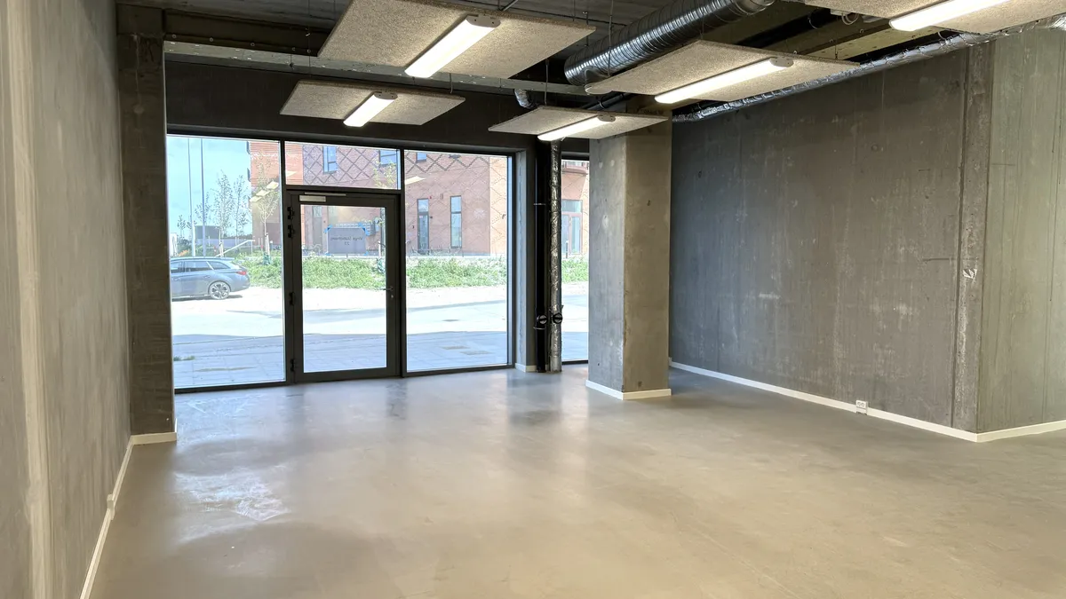 Store kontorlokation med lyse og åbne vinduer, store glasdøre og højloft. Ingen møbler eller andet udstyr på billedet