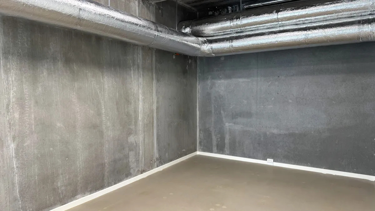En rummelig kontorlokal i Frederikssund med betonvægge, hvide gulve og gulve. Væggene er belagt med aluminium og tekstil.