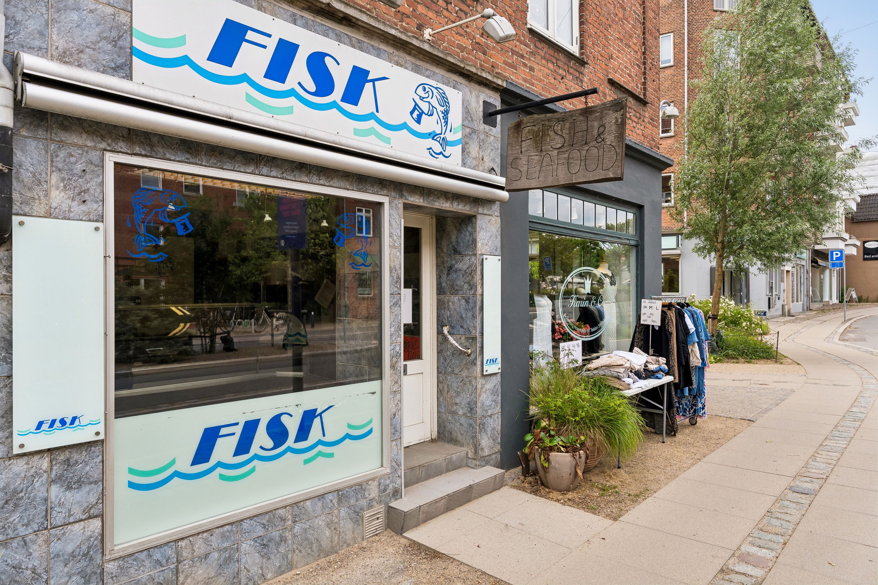 Fiskehandel Fisk på Søborg Hovedgade. Butik med glasruder og blå fisk i vinduet. Butikken har et skilt med teksten Fisk og Seafood
