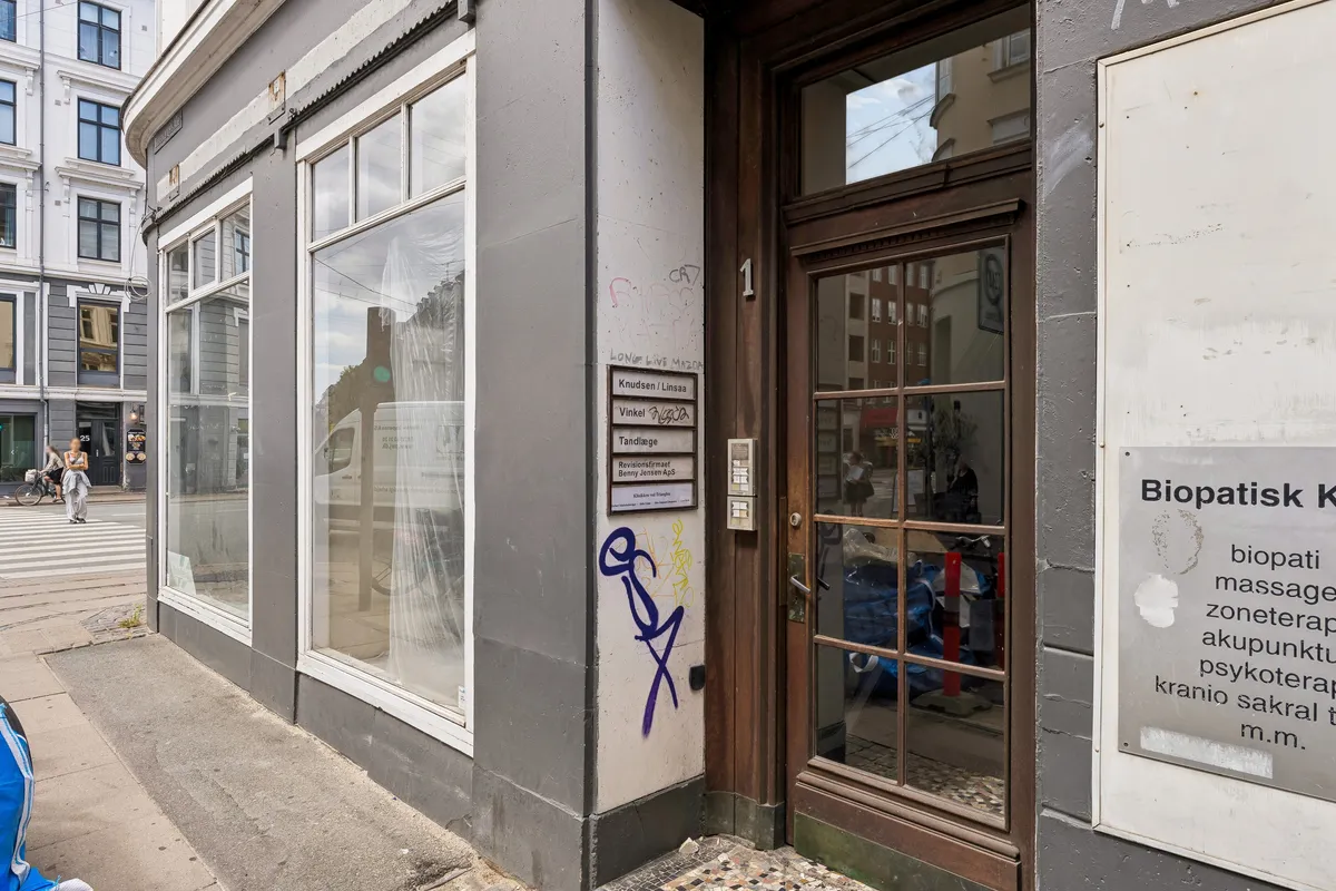 Kontor til leje på Rosenvængets Allé 1, 1. tv, 2100 København Ø. Bygningen med glasvinduer, skilte og graffiti er placeret ved siden af en gågade og en gåbro
