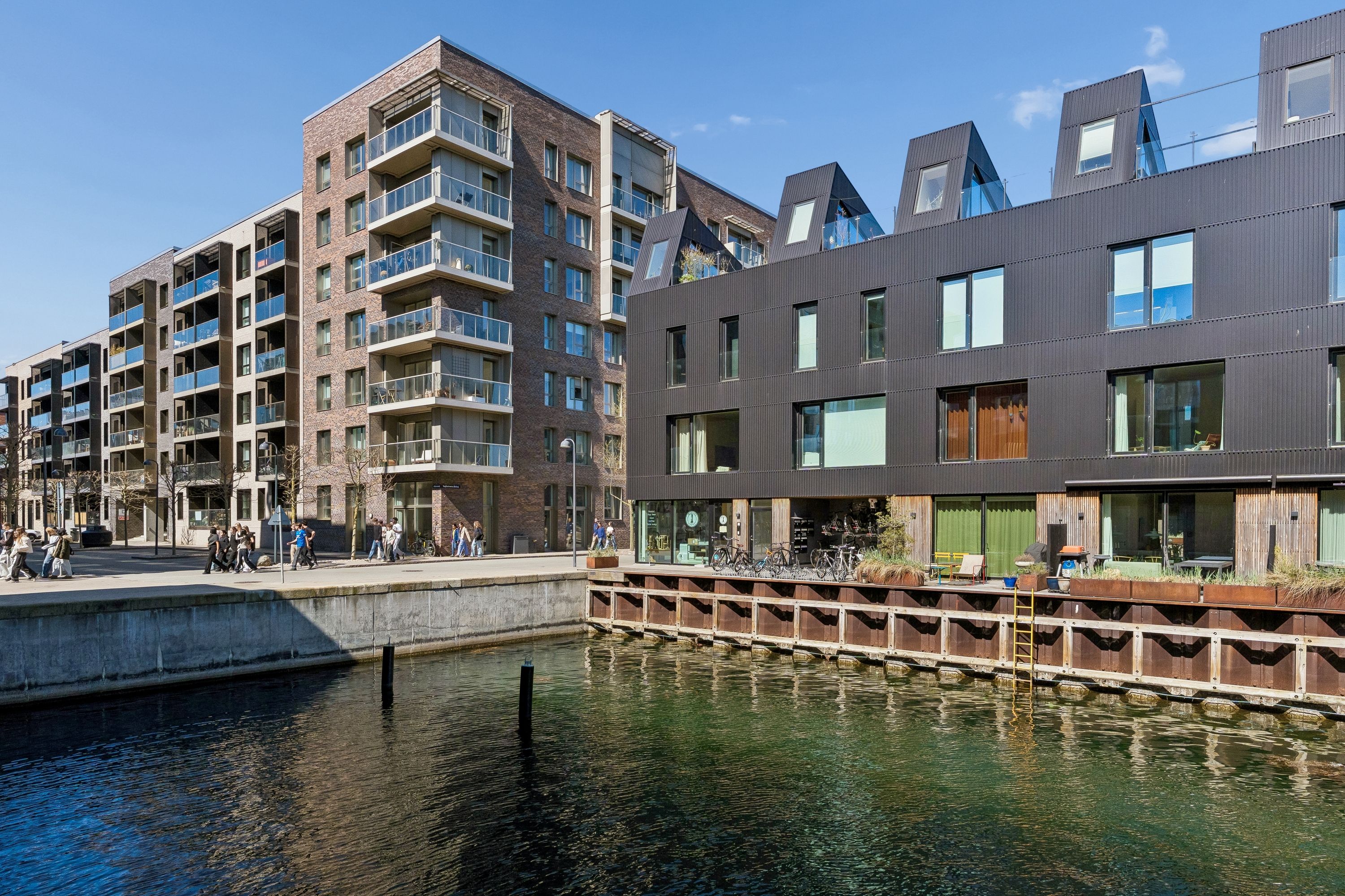 Moderne kontorlokaler i stueplan på Teglholmens Østkaj med udsigt over vandet og terrasse med planter og blomster.