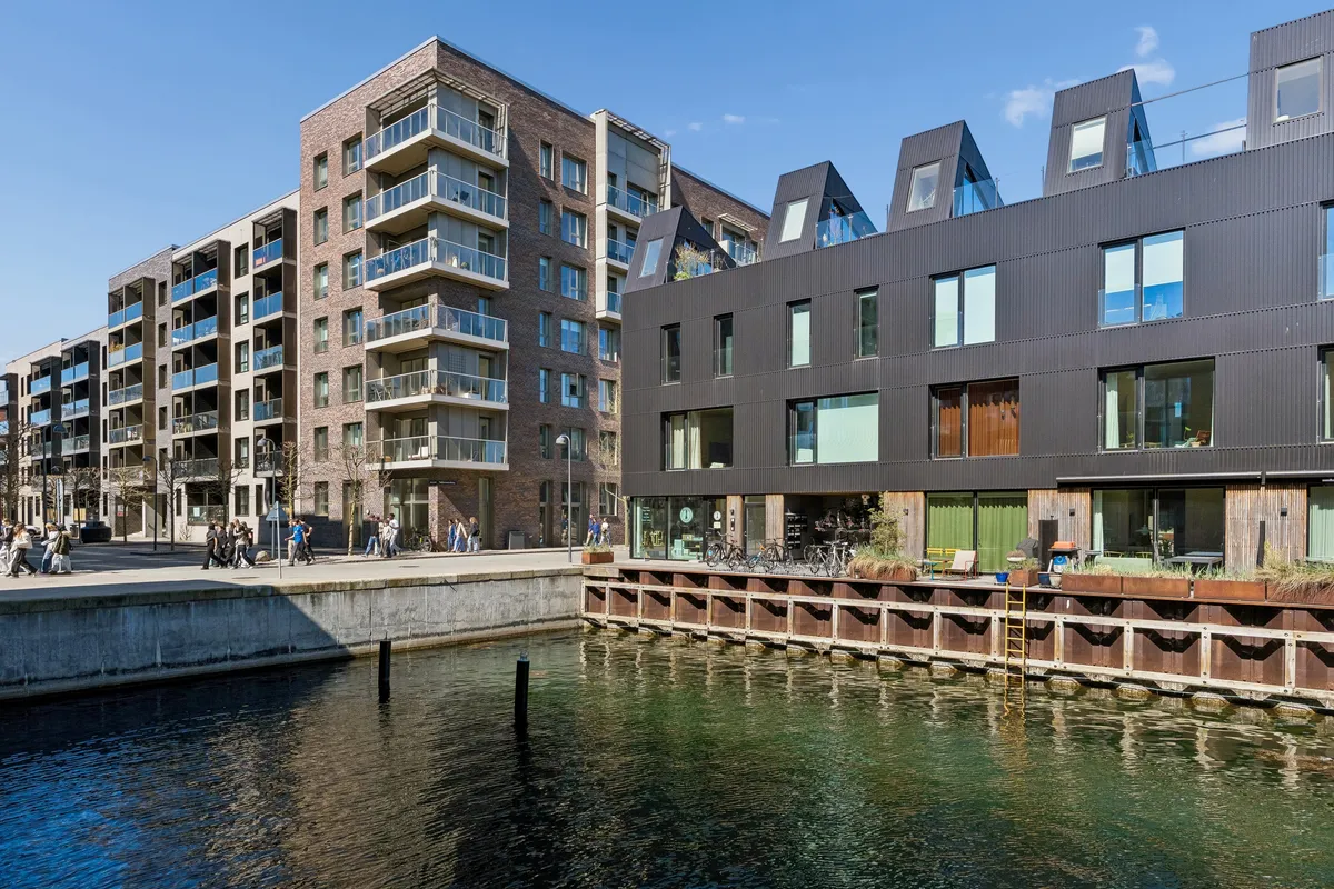 Moderne kontorlokaler i stueplan på Teglholmens Østkaj med udsigt over vandet og terrasse med planter og blomster.