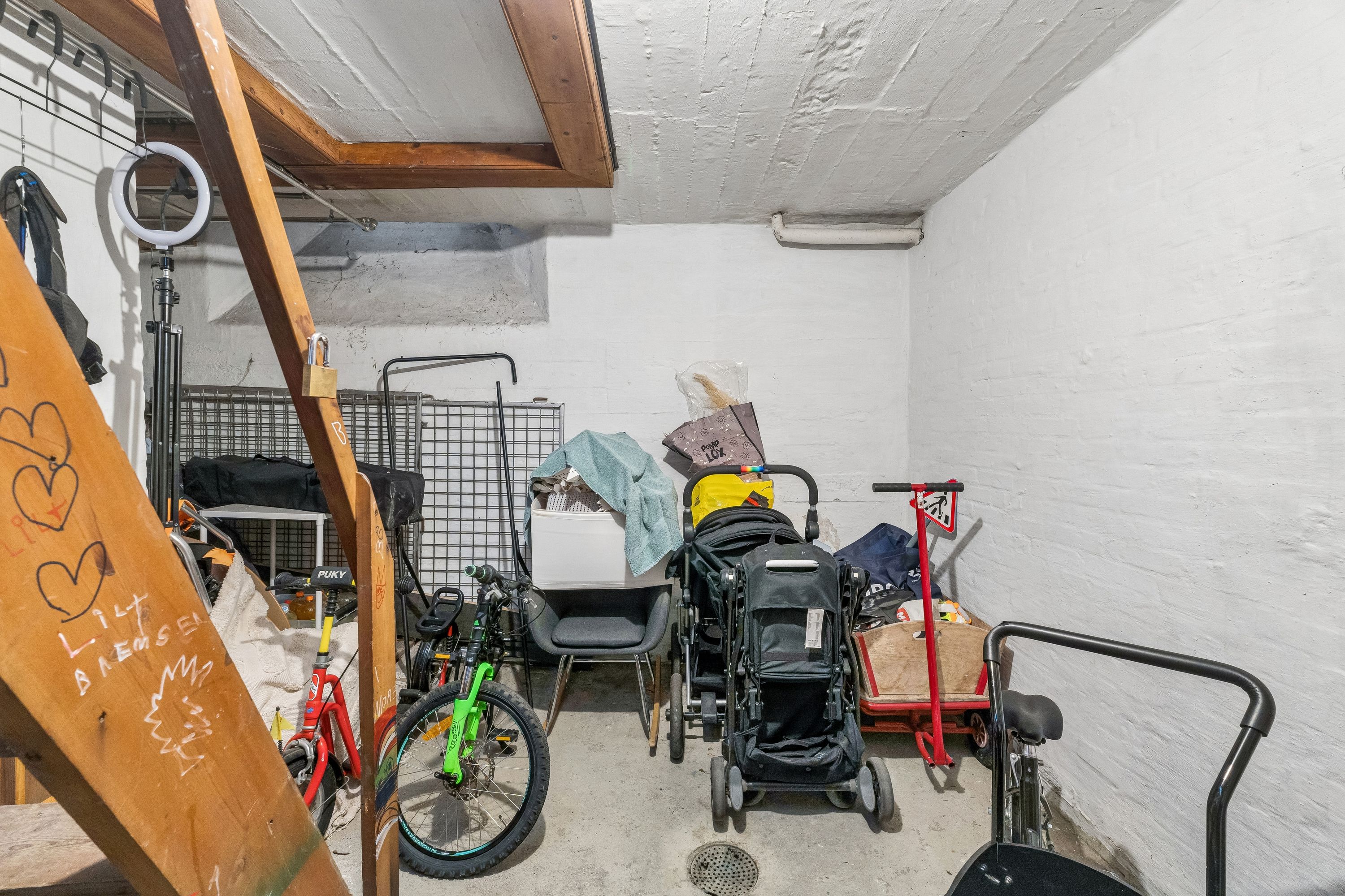 Lokal til leje med skrånende loft og højdepunkter som cykler, kørestola, støvsuger og diverse udstyr samt kæledyrs træ skulptur i loftet