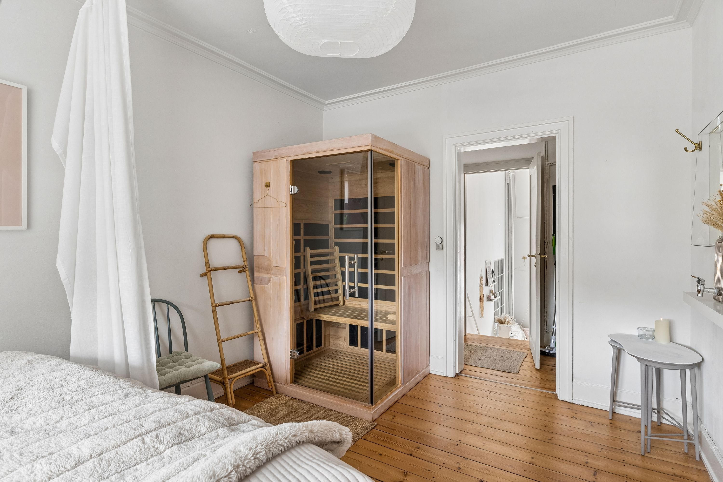 En soveværelse med hvidt sengetøj og et træpanel med et saunakabine og en stang med et hvidt gardin