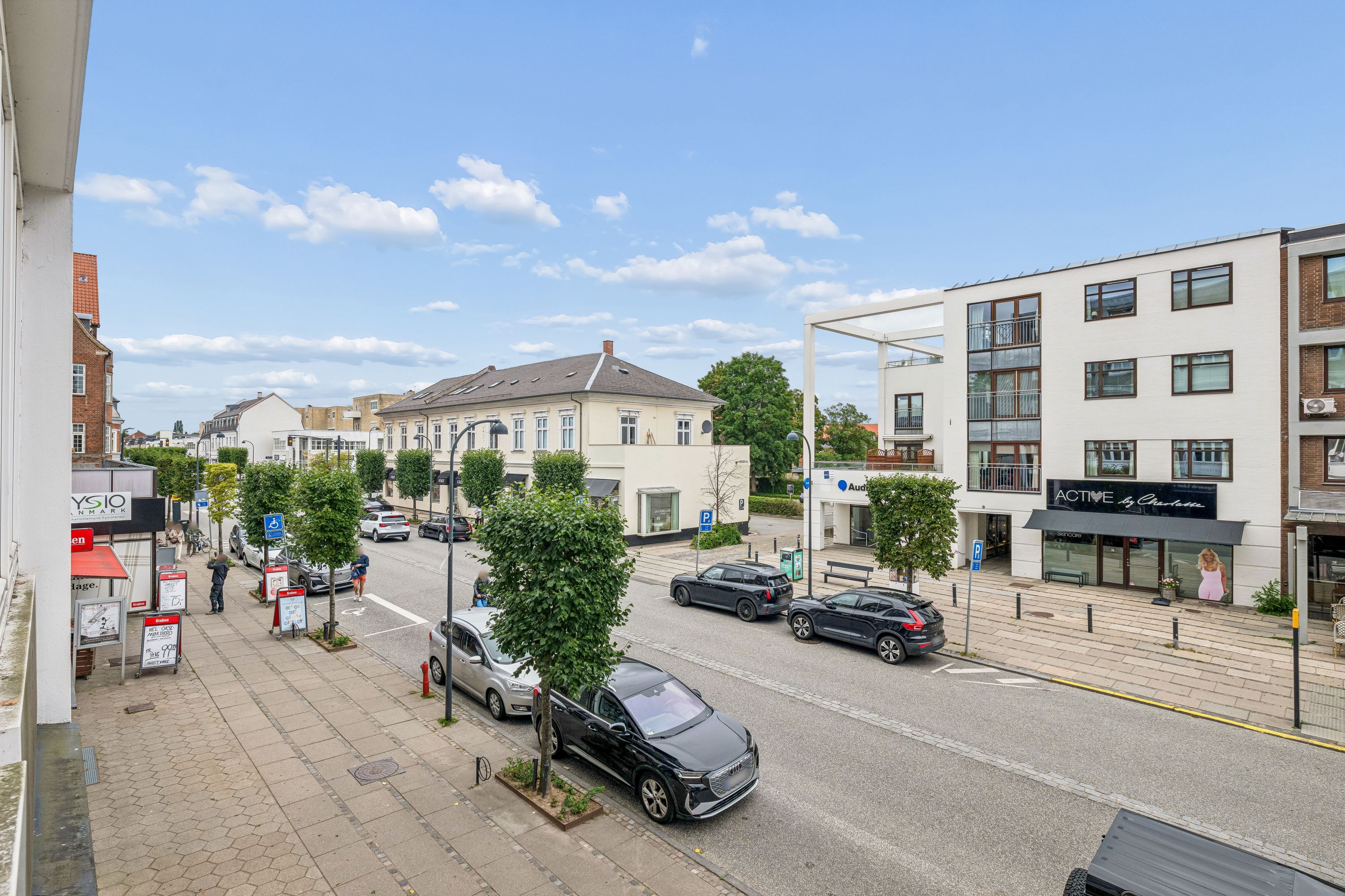 Kontor og klinik til leje på Jægersborg Alle 19 i Charlottenlund. Adgang til parkeringsplads. Bygning med parkeringsplads og gågade med butikker og biler.