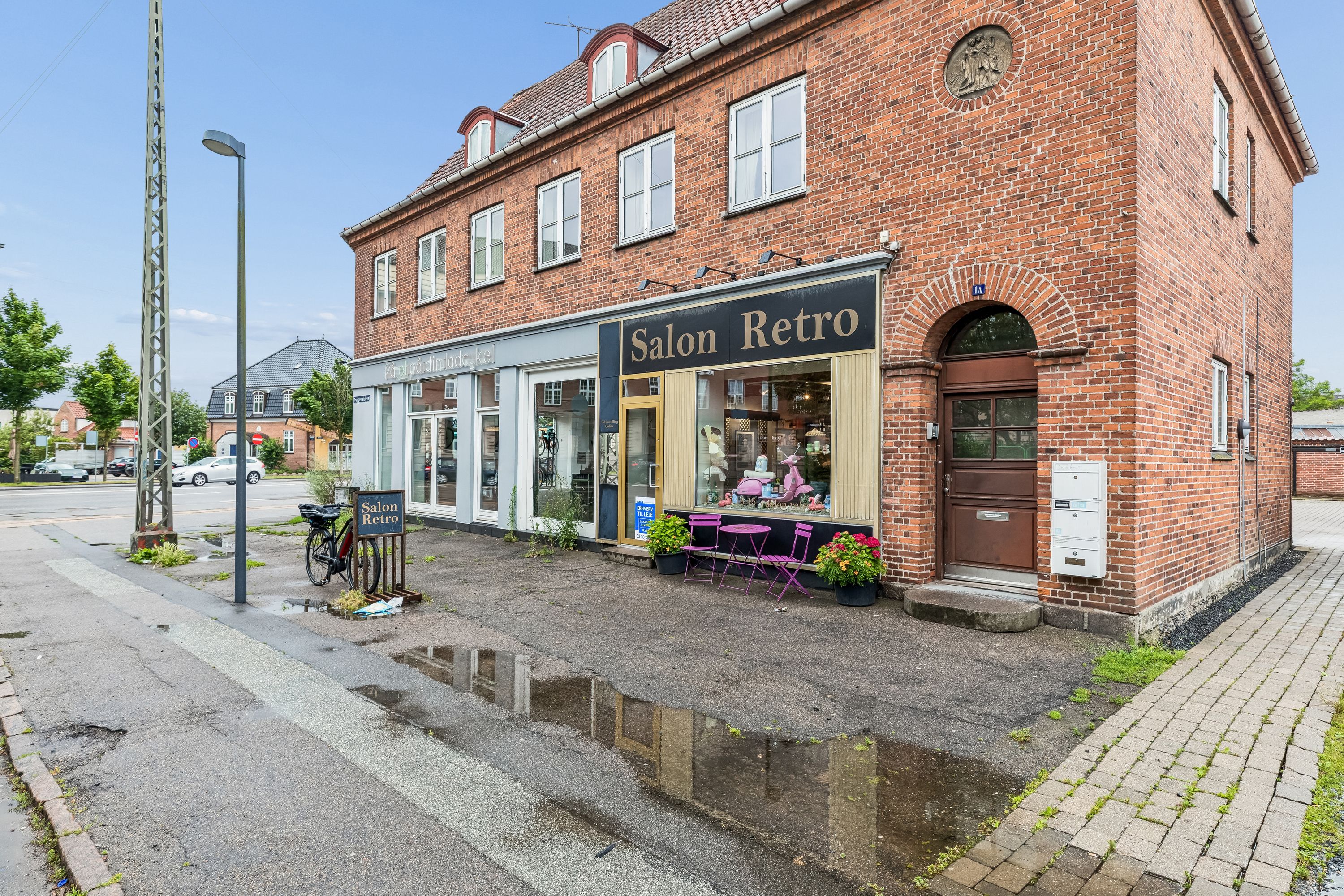 Lejlighed med lejetøj butik Salon Retro. Farverige stolene og borde udenfor butikken og blomster på gulvet