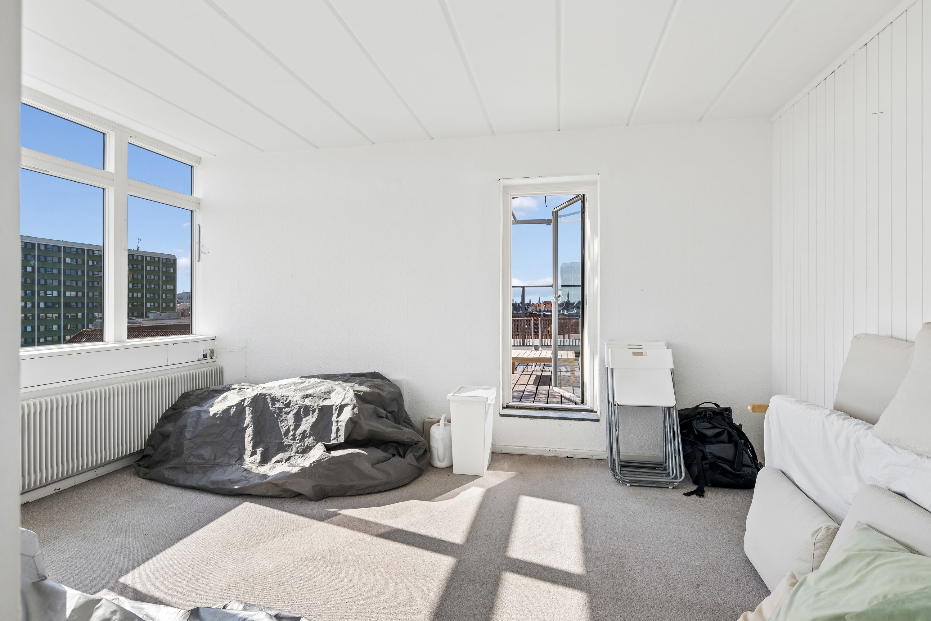Kontorlokaler med en stor sofa og to høje vinduer med terrasseudgang og en terrasse med udsigt over byen og træbord og stole