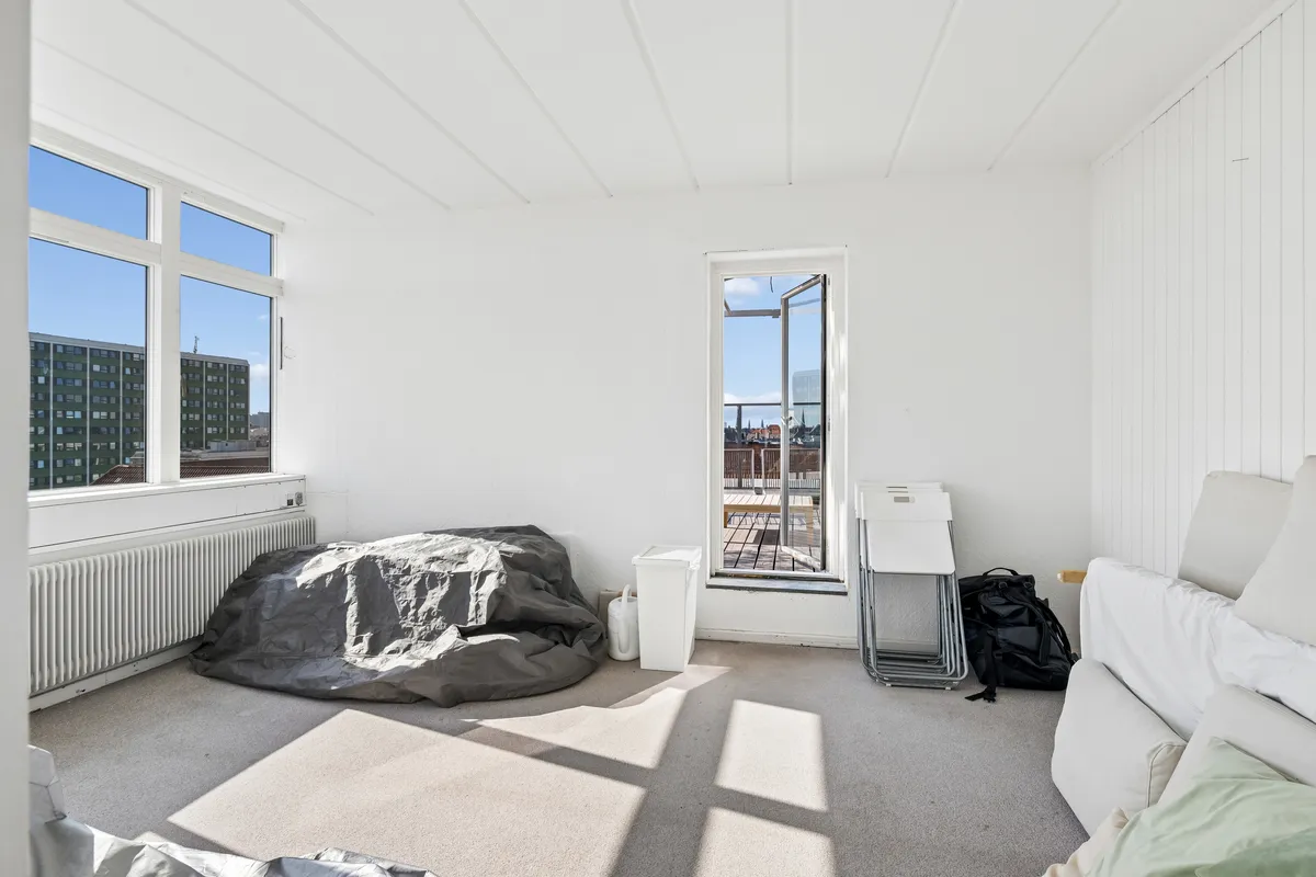 Kontorlokaler med en stor sofa og to høje vinduer med terrasseudgang og en terrasse med udsigt over byen og træbord og stole