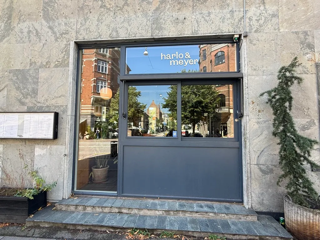 Harlo & Meyer bageri og delikatesse med udendørs terrasse og krydrede plantepot i forgrunden