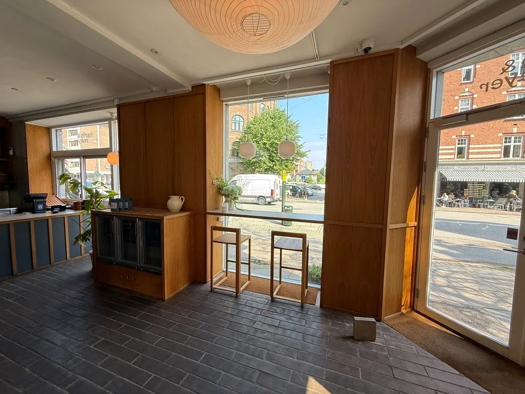 Take-away, bageri og deli i frederiksberg til afståelse på gammel kongevej 107. Butikken er udstyret med en køkkendel, vinduer og et værelse med stole og bord.