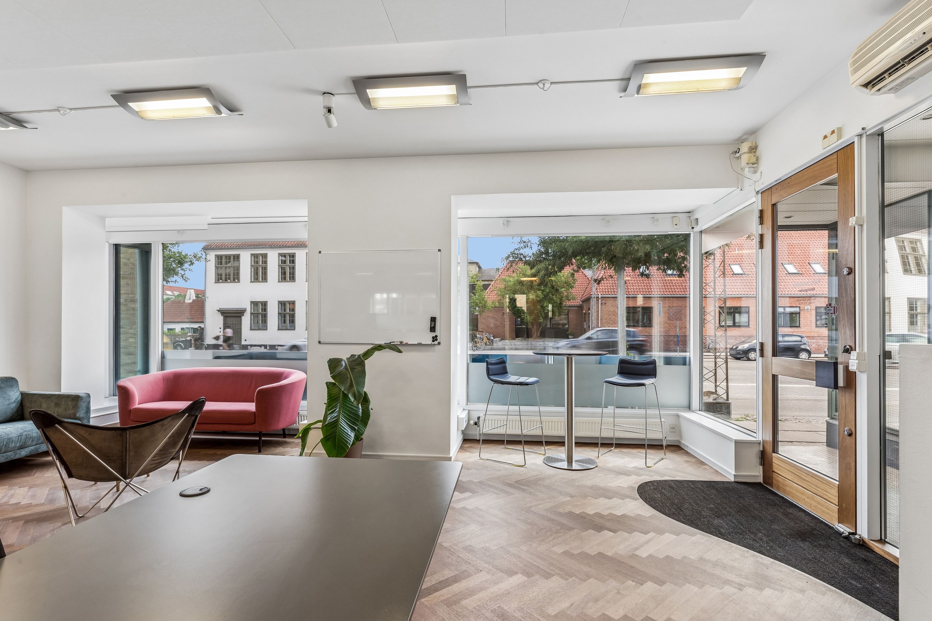 Lejlighed med solrigt stueplan og terrasse, smagfuldt indrettet med moderne møbler og grønne planter i lyse interiører og glasdøre