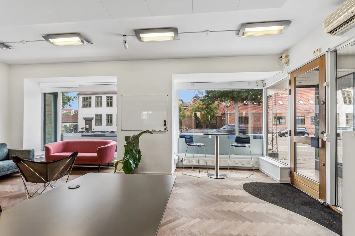 Lejlighed med solrigt stueplan og terrasse, smagfuldt indrettet med moderne møbler og grønne planter i lyse interiører og glasdøre