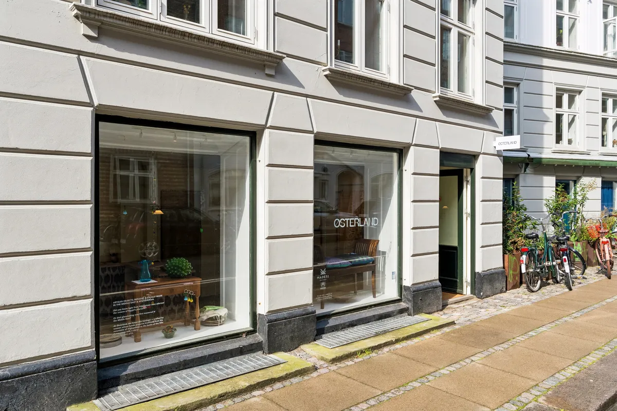 Kontor til leje på Egegade 7 med lyse og store vinduer, hvor det er muligt at se indretningen indefra. Københavnsgade med cykler og planter langs gaden