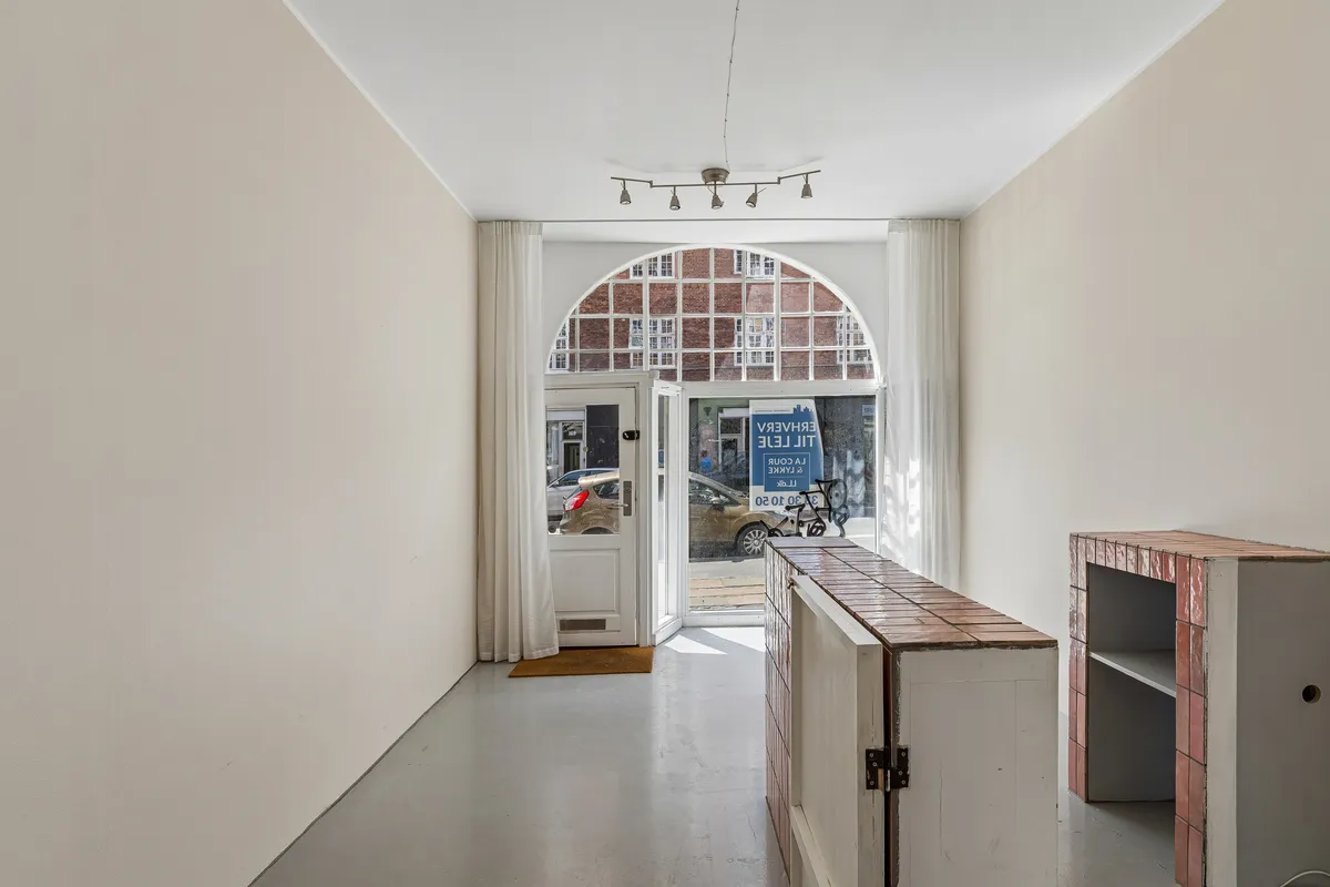 Store glasruder og lysegule vægge i erhvervslokaler på Vesterbrogade 180, st. 1. Lyskroner hænger i loftet, og der er trægulv foran døren