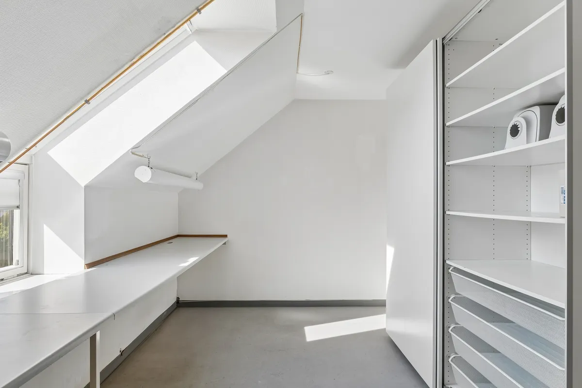 Et lyst og veludstyret kontor med lyse lofter, store vinduer og moderne møbler