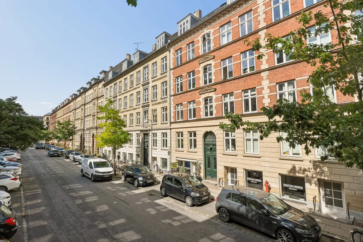 Rækkehus med kontorlokaler på Roarsvej 6, 2000 Frederiksberg. Mange parkerede biler og træer langs gaden og husene