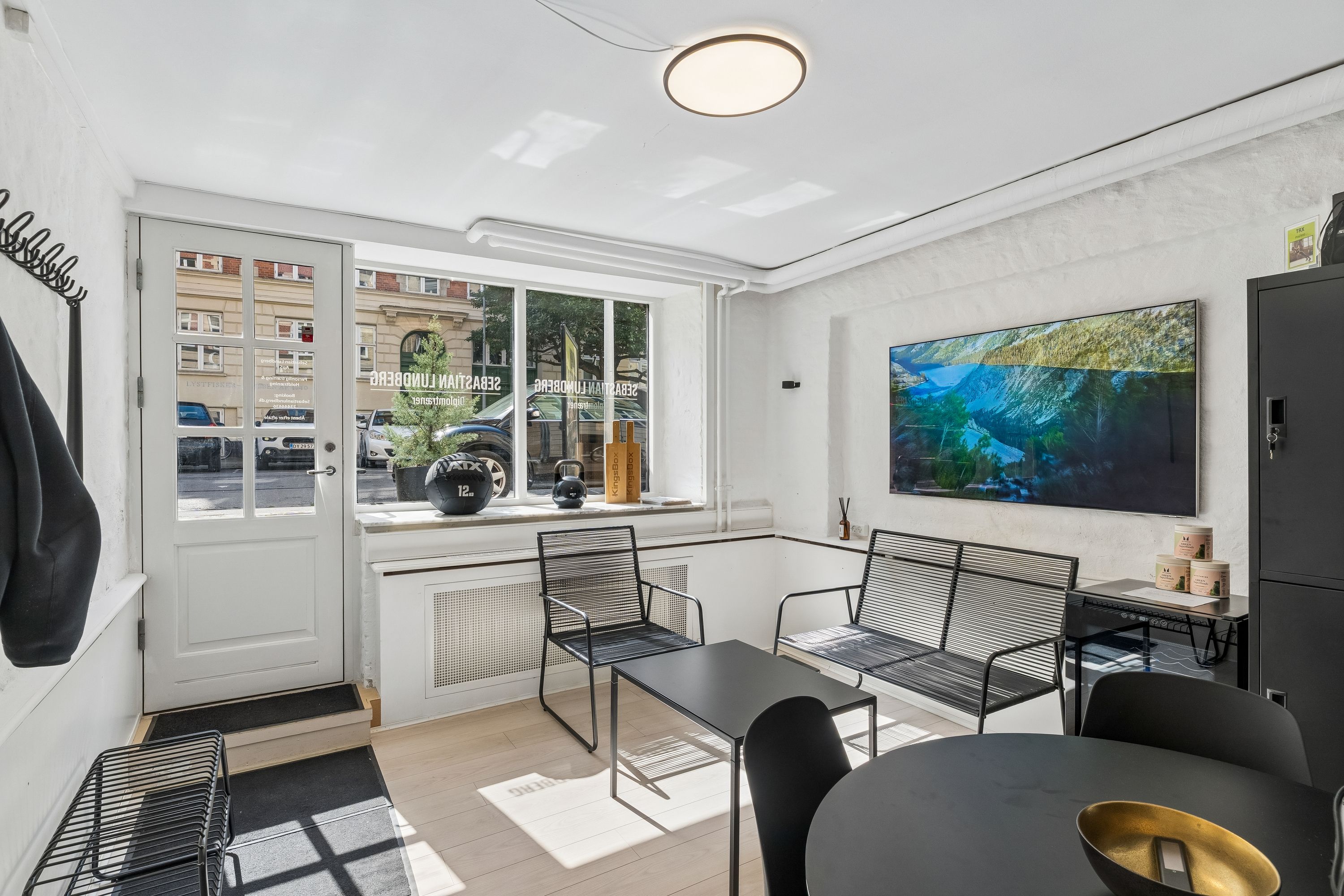 Kontor til leje i Frederiksberg med moderne indretning, åbent vinduesparti, tv på væggen, moderne møbler og lyse loftslamper