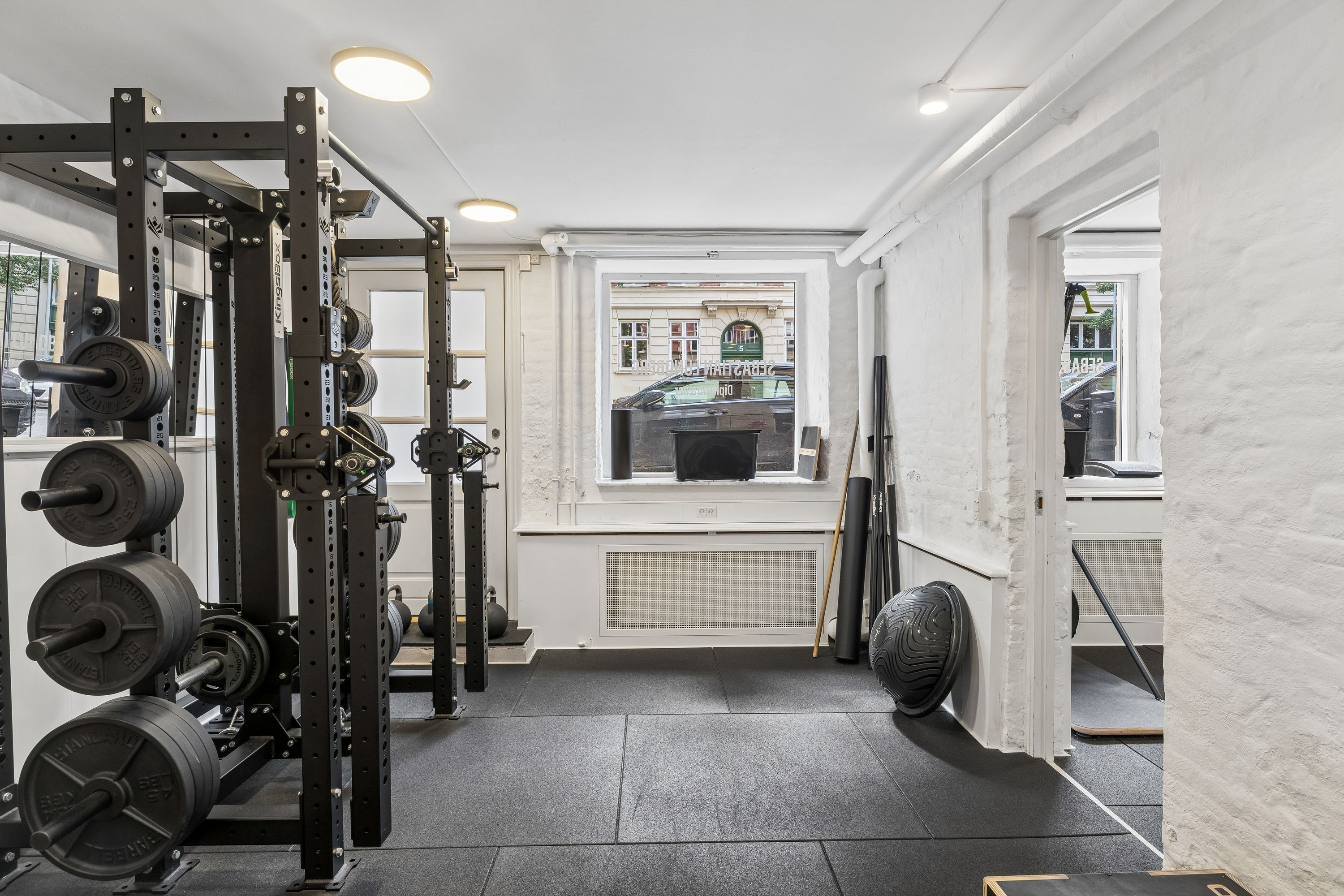 Gym med barbell, kettlebell, trækapparater, stang og vinduer med byudsigt til Roarsvej 6, Frederiksberg